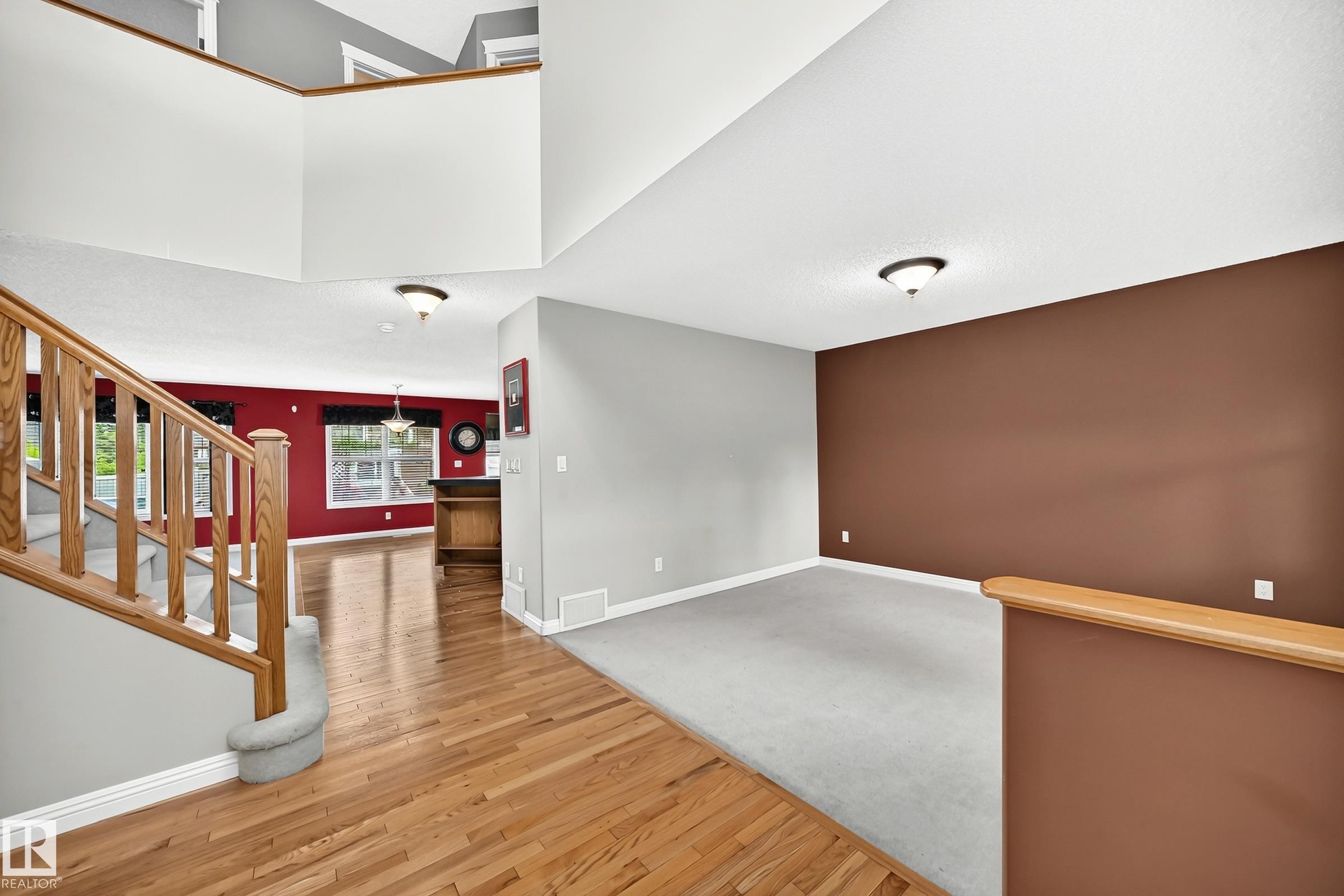Two-story entryway featuring a wood-finish staircase with carpeted treads - 2523 Pegasus Boulevard, Edmonton, AB