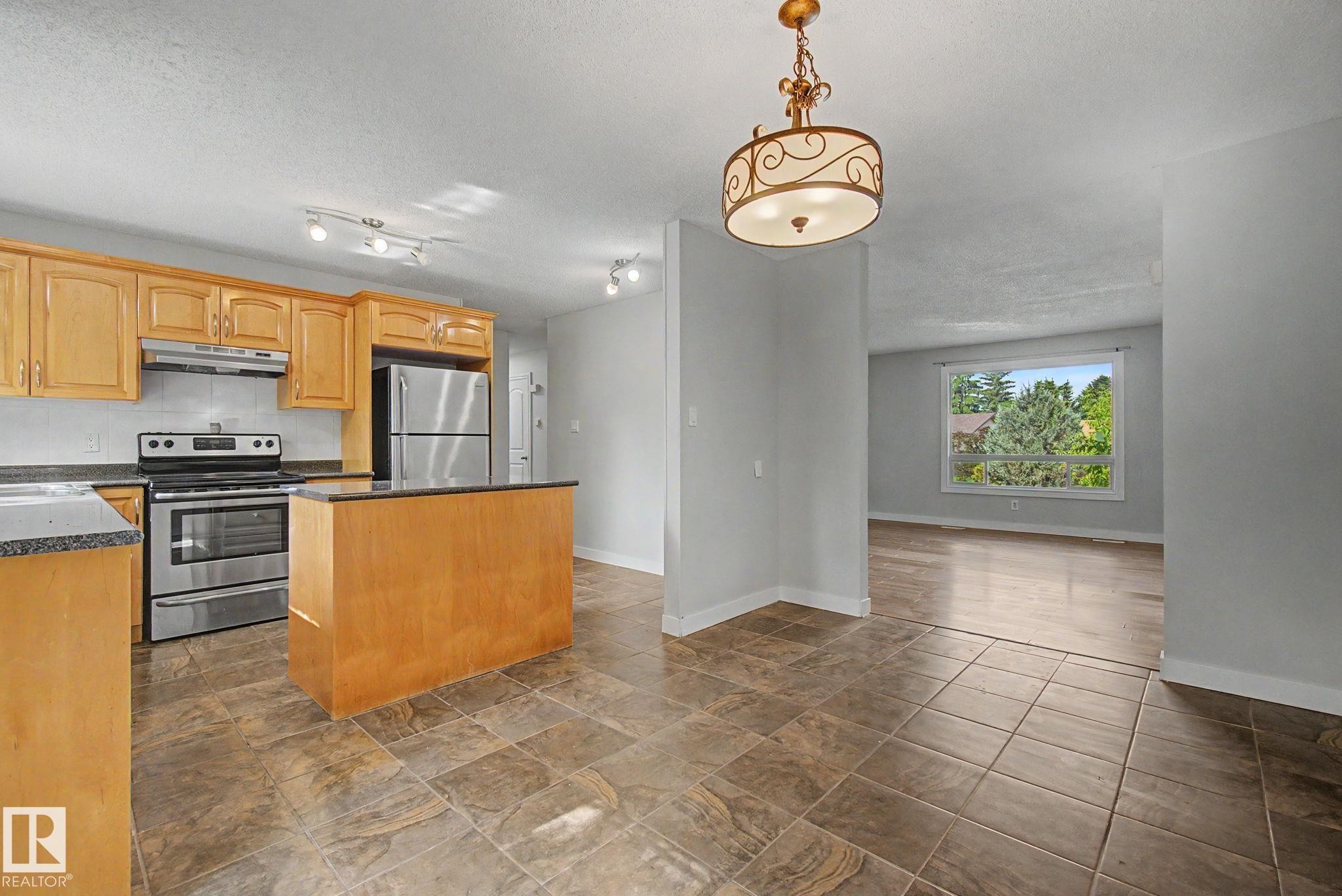 Kitchen featuring wood cabinetry, stainless steel appliances, and dark countertops - 1511 75 Street, Edmonton, AB