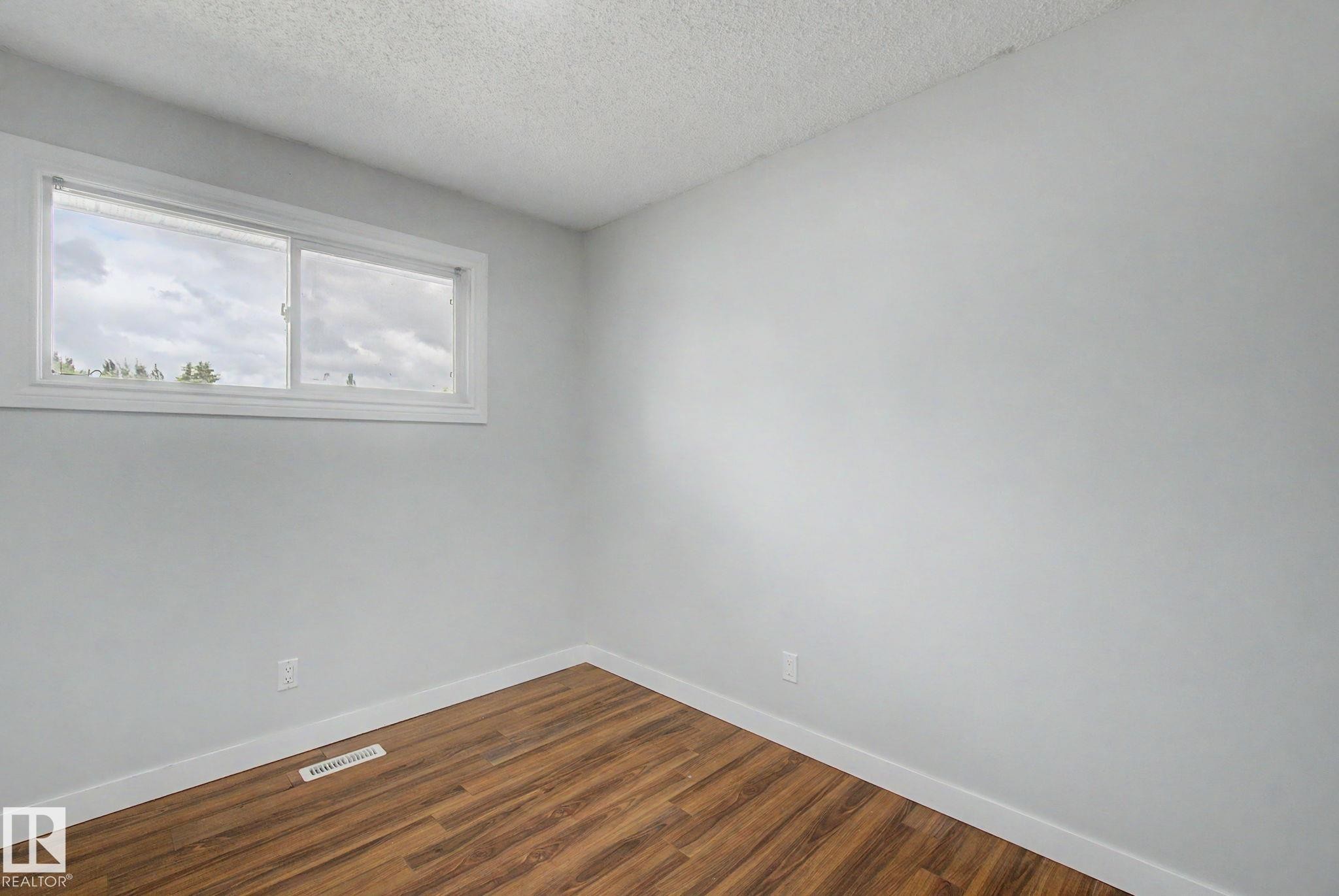Windowed room featuring wood-finish flooring, light gray walls, white baseboards, and a white window frame - 1511 75 Street, Edmonton, AB