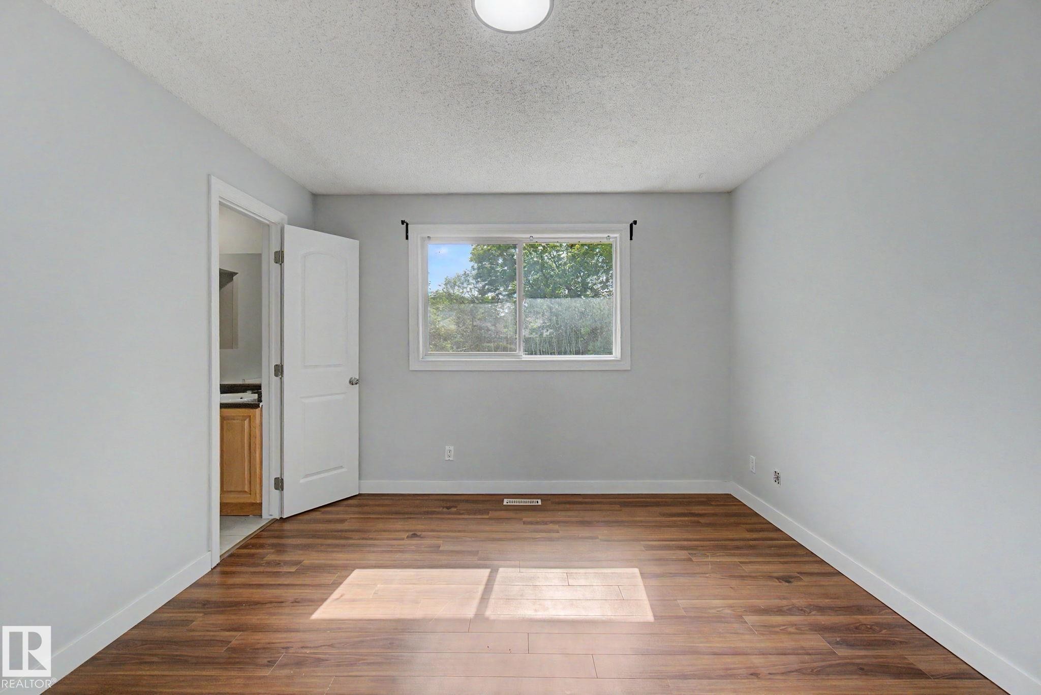 Bright interior space featuring wood-finish flooring, light grey walls, and a white trim package - 1511 75 Street, Edmonton, AB