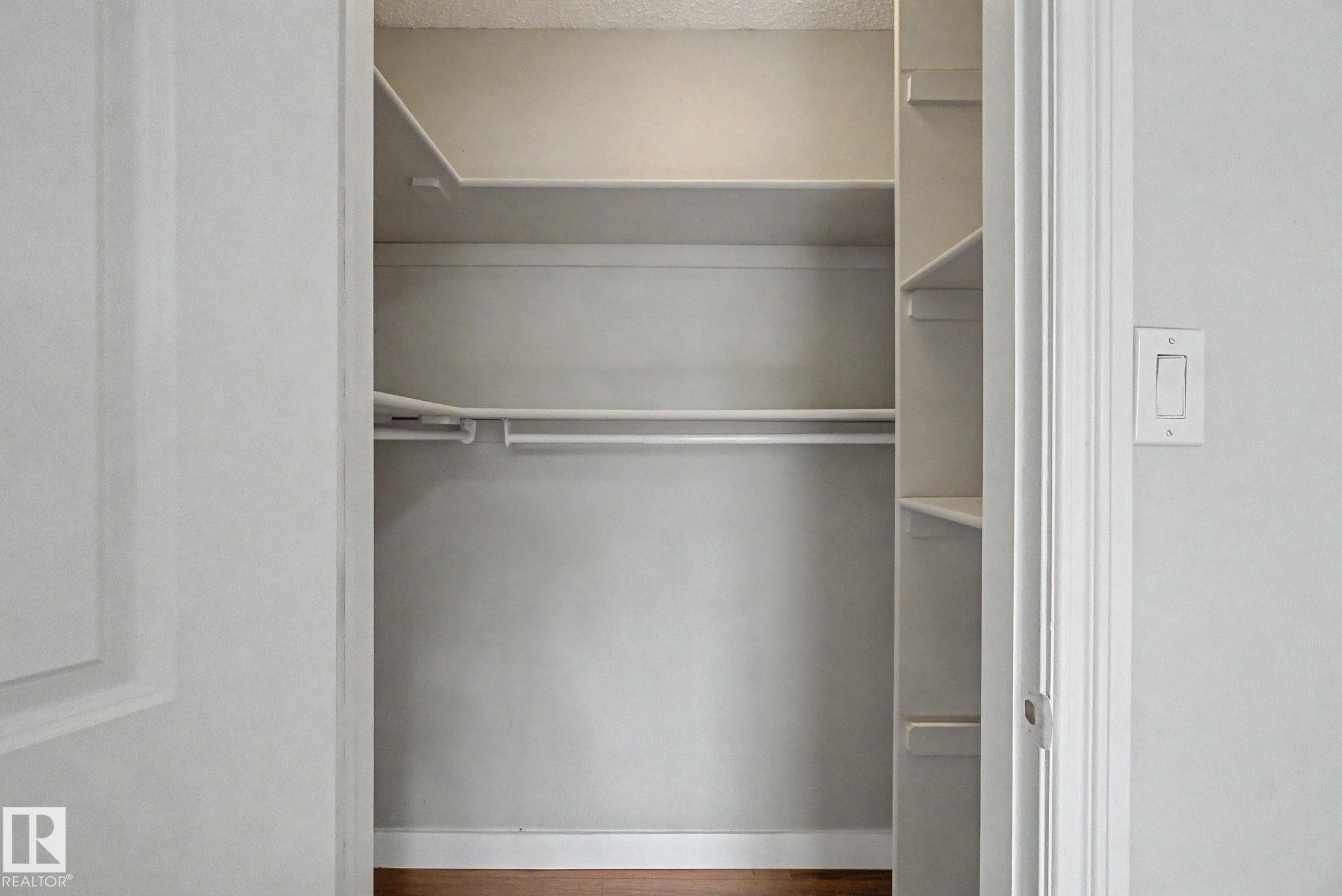 Built-in closet system featuring multiple shelves and hanging rods, wood-finish flooring, and white painted walls - 1511 75 Street, Edmonton, AB