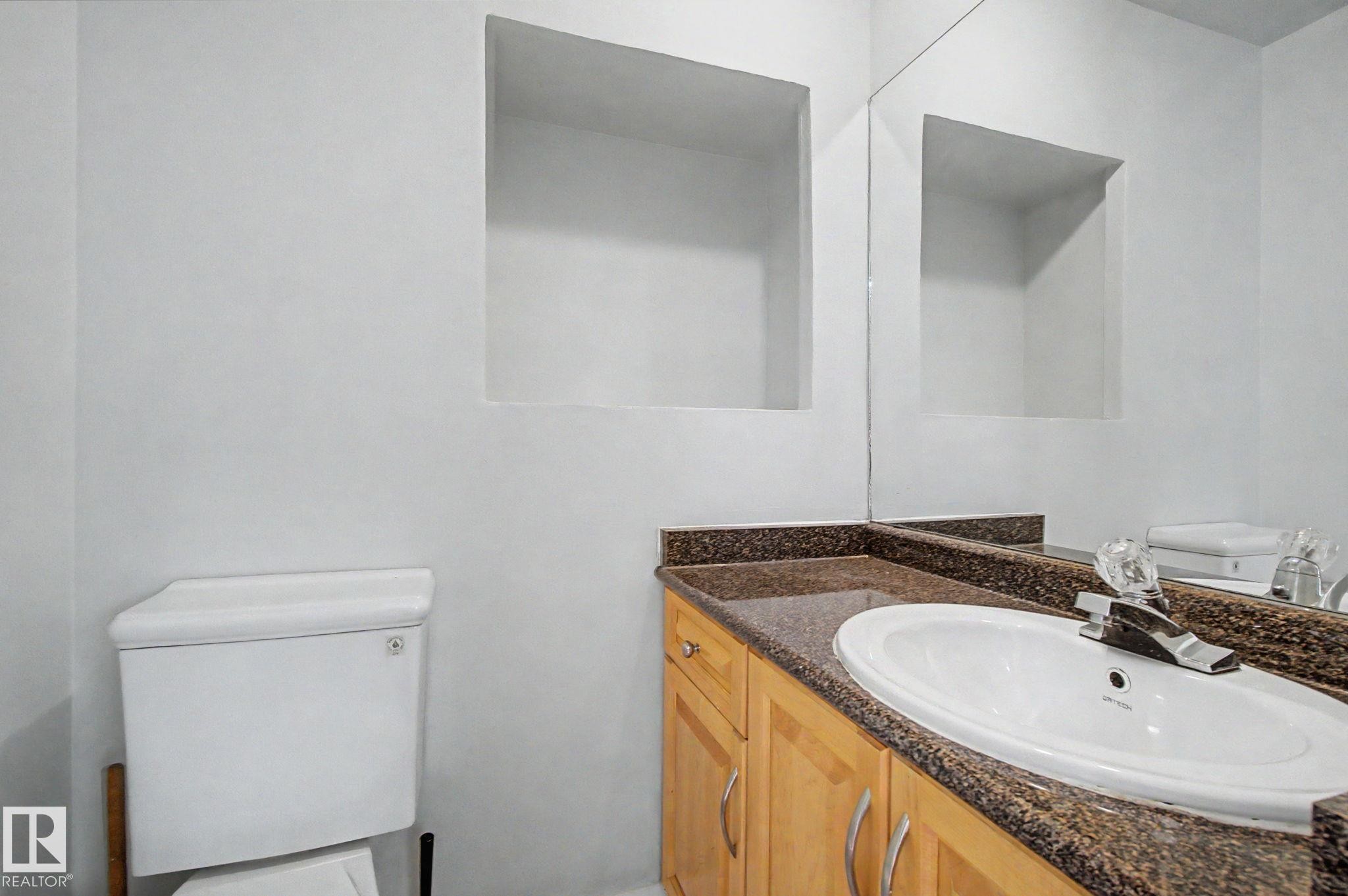 Bathroom vanity featuring light wood cabinetry, a granite countertop, and an undermount sink - 1511 75 Street, Edmonton, AB