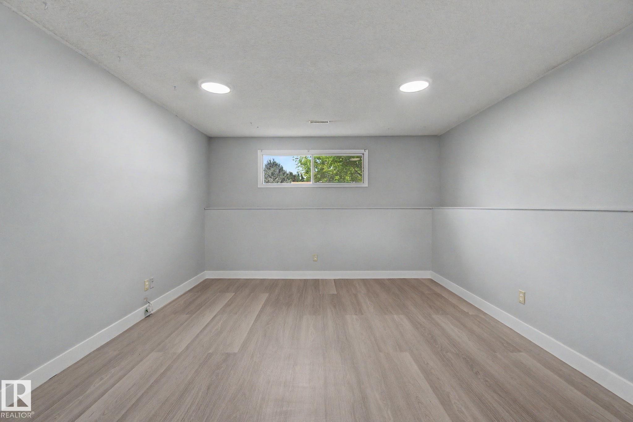 Spacious room featuring wood-finish flooring, light gray walls, and recessed lighting - 1511 75 Street, Edmonton, AB