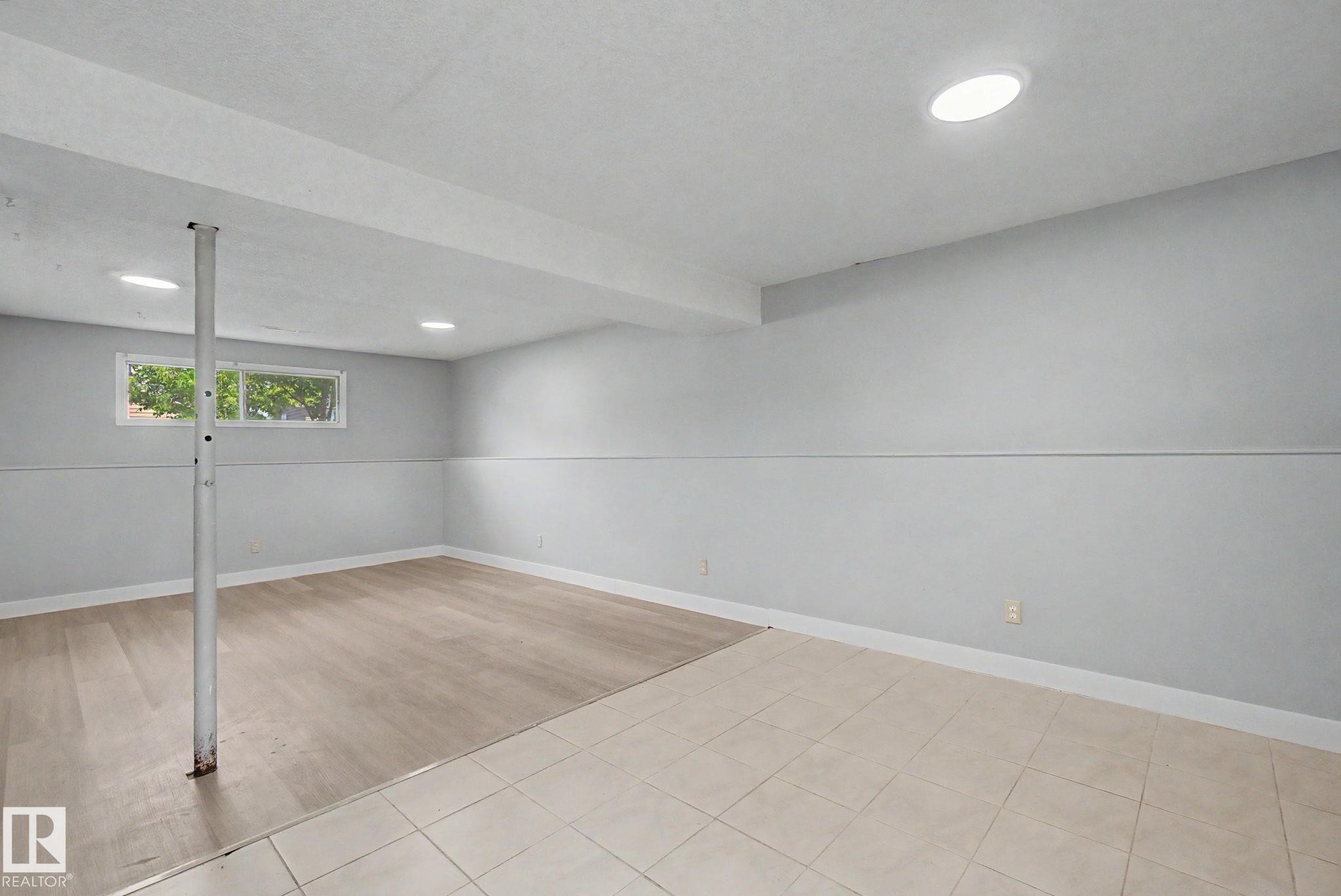 Spacious lower level room featuring recessed lighting, a window, wood-finish flooring, and light-toned tile flooring - 1511 75 Street, Edmonton, AB