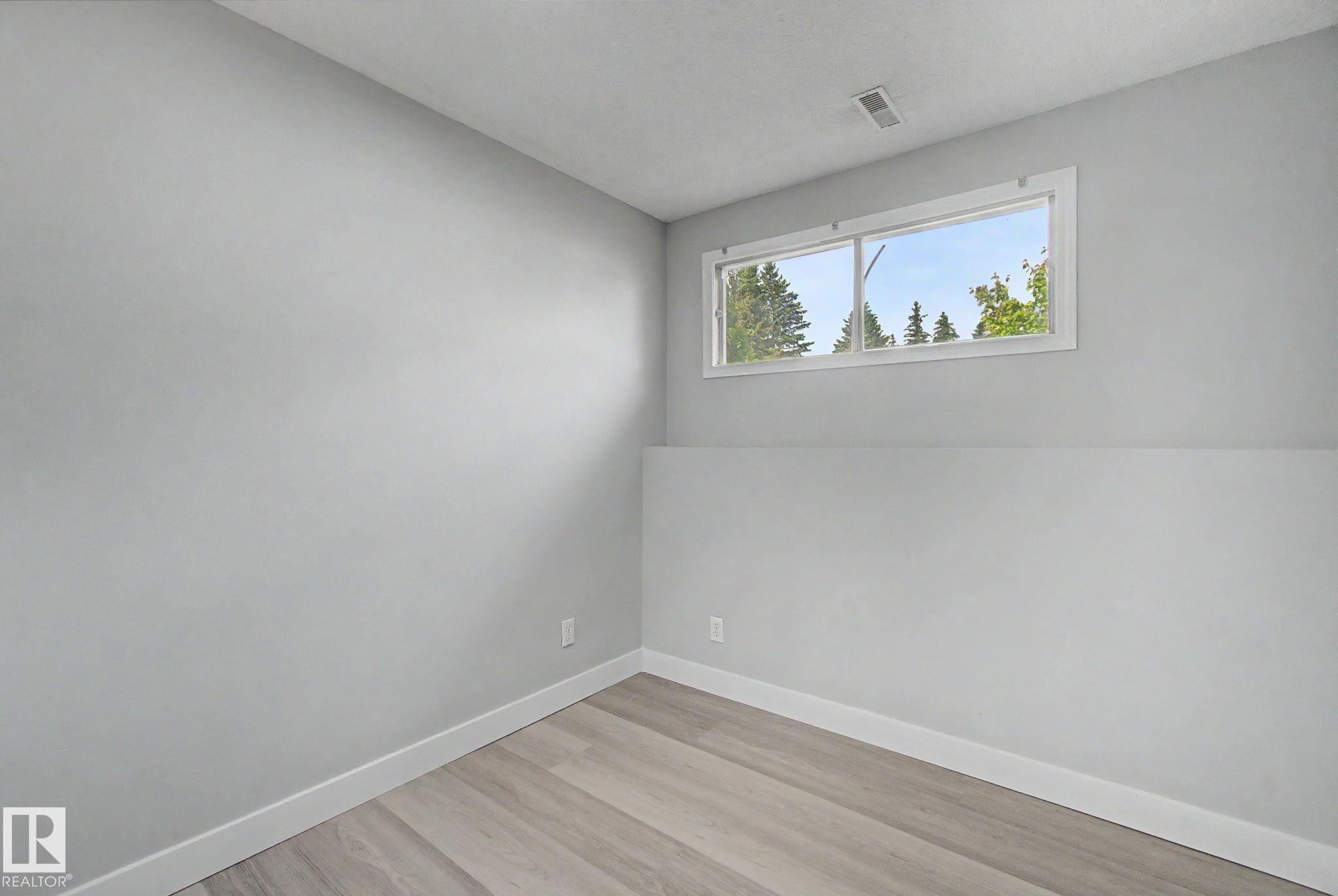 Interior room featuring light gray walls, white trim, and wood-finish flooring - 1511 75 Street, Edmonton, AB