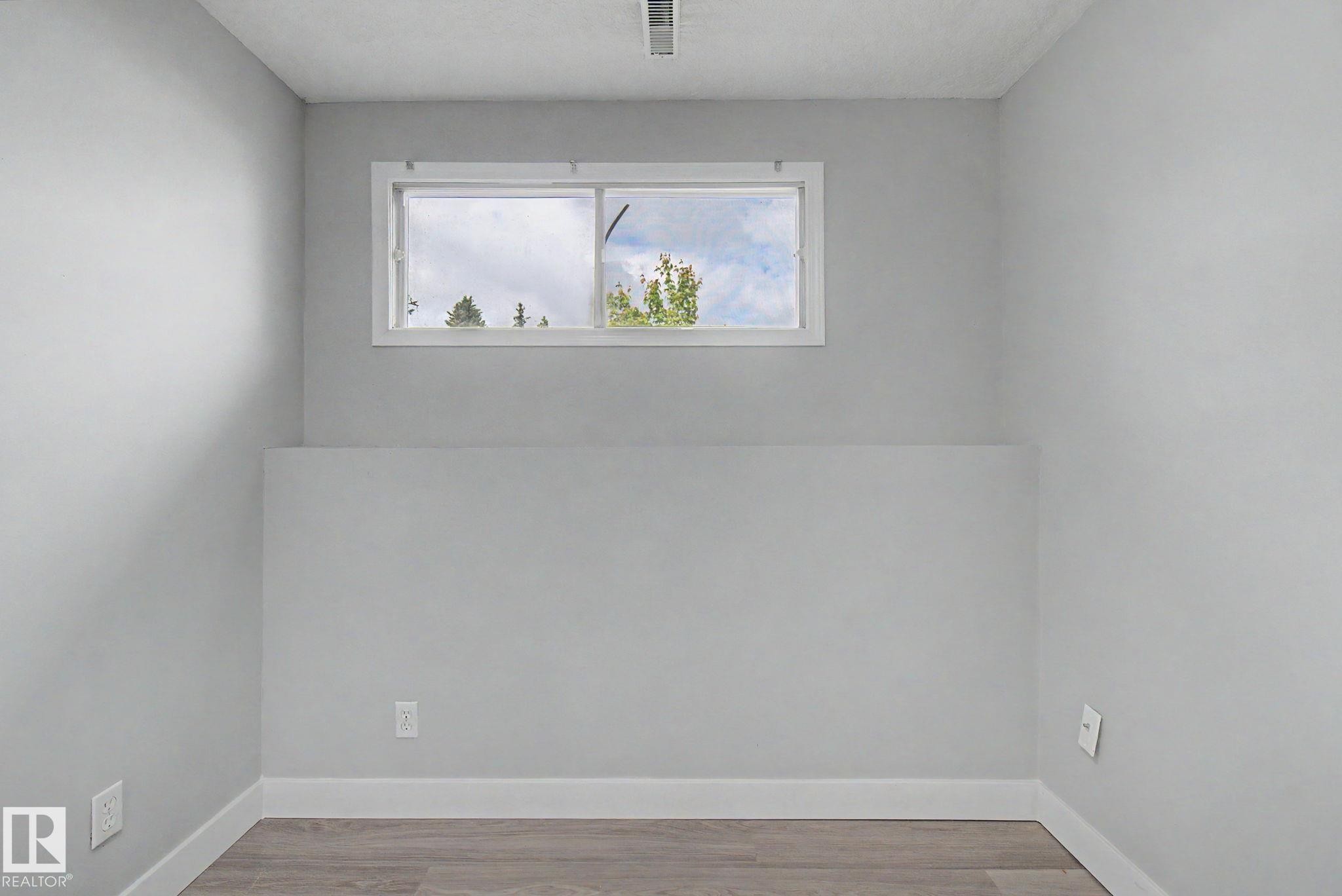 Room featuring light gray walls, white trim, and wood-finish flooring - 1511 75 Street, Edmonton, AB