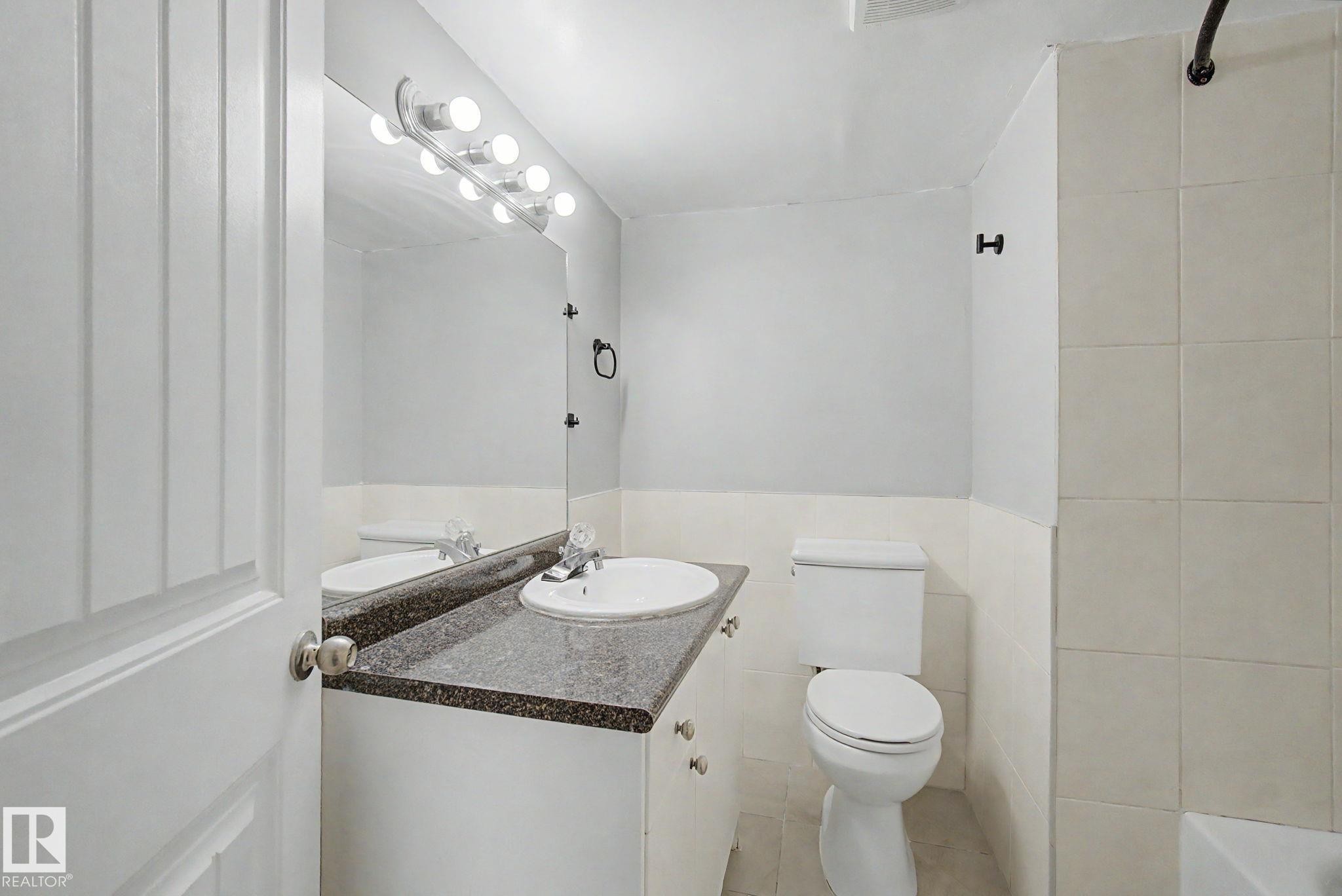 Bathroom featuring a white vanity with a dark countertop, an integrated sink, and an overhead light fixture - 1511 75 Street, Edmonton, AB