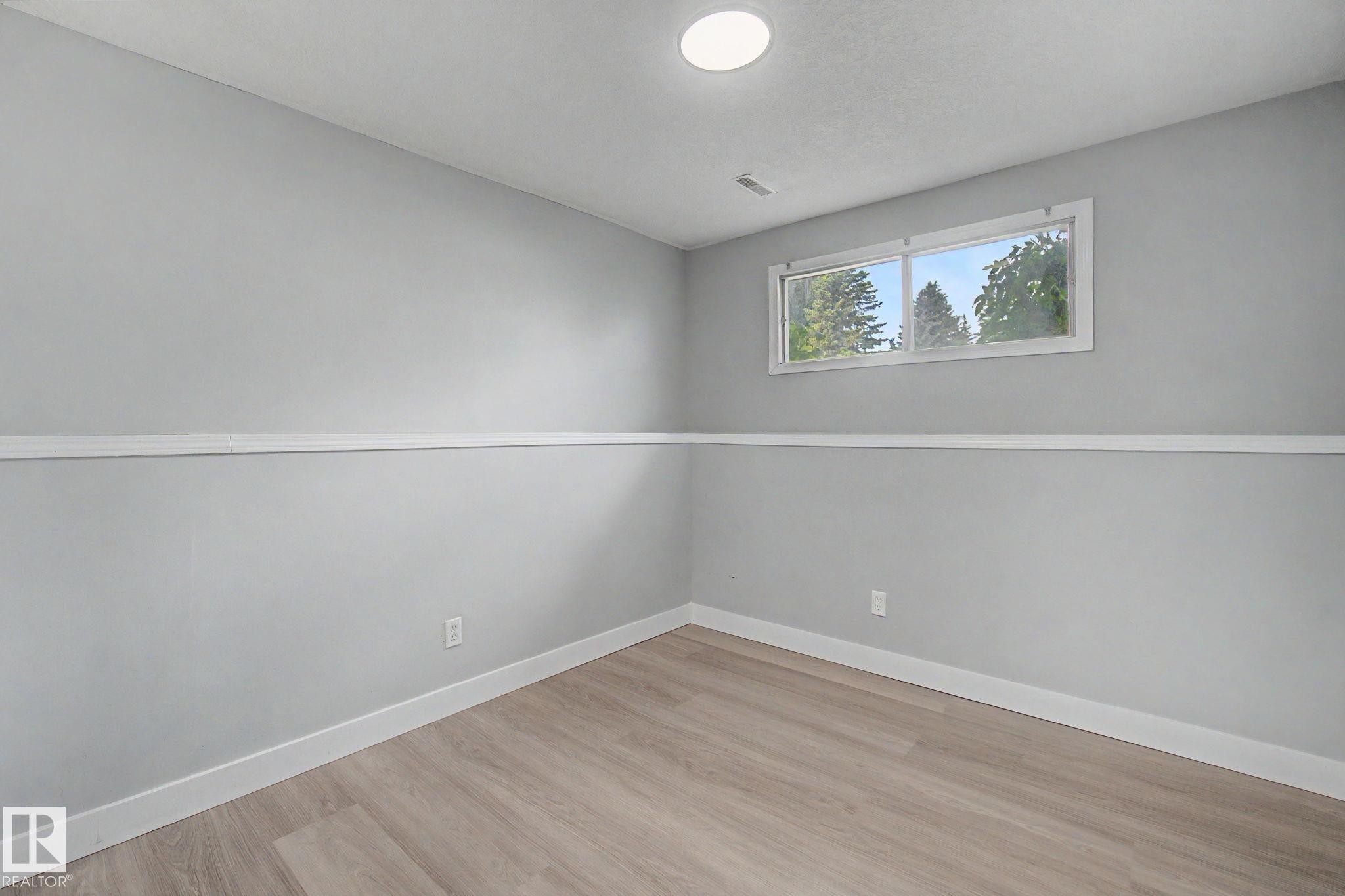 Neutral gray walls with white chair rail molding, wood-finish flooring, a double window, and recessed lighting - 1511 75 Street, Edmonton, AB