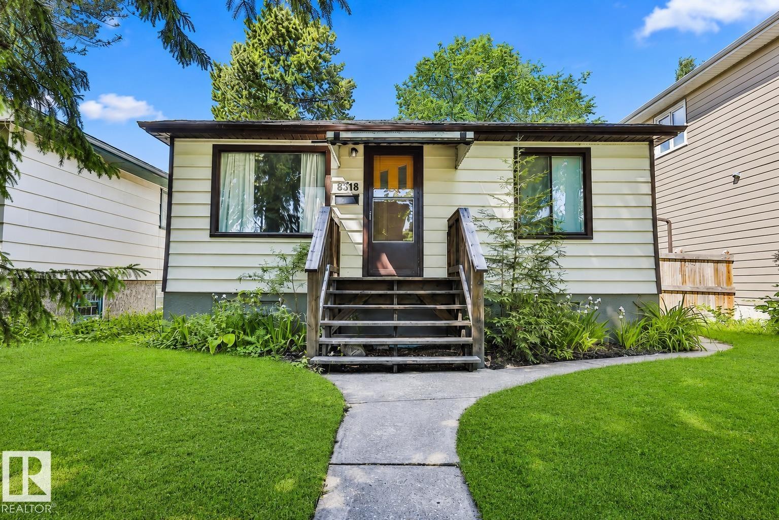 Single-story residence featuring light-colored horizontal siding, dark window trim, and a dark entry door - 8318 80 Avenue, Edmonton, AB