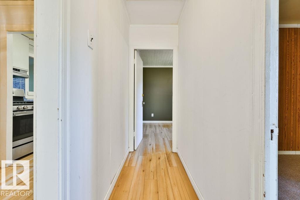 Hallway featuring wood-finish flooring, white panel walls, and white trim - 8318 80 Avenue Nw, Edmonton, AB - Indoor Photo Showing Other Room