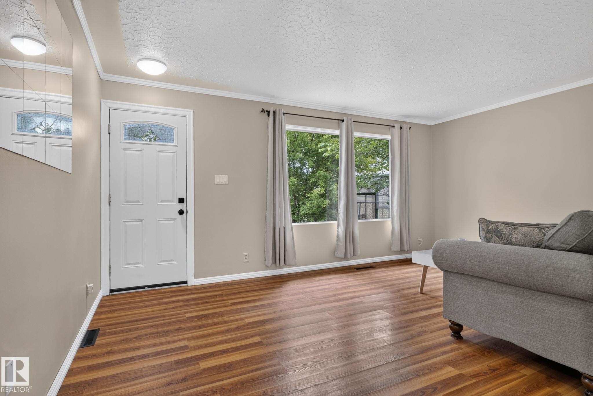 Entryway featuring wood-finish flooring and a white paneled door with decorative glass - 12952 114 Street Nw, Edmonton, AB