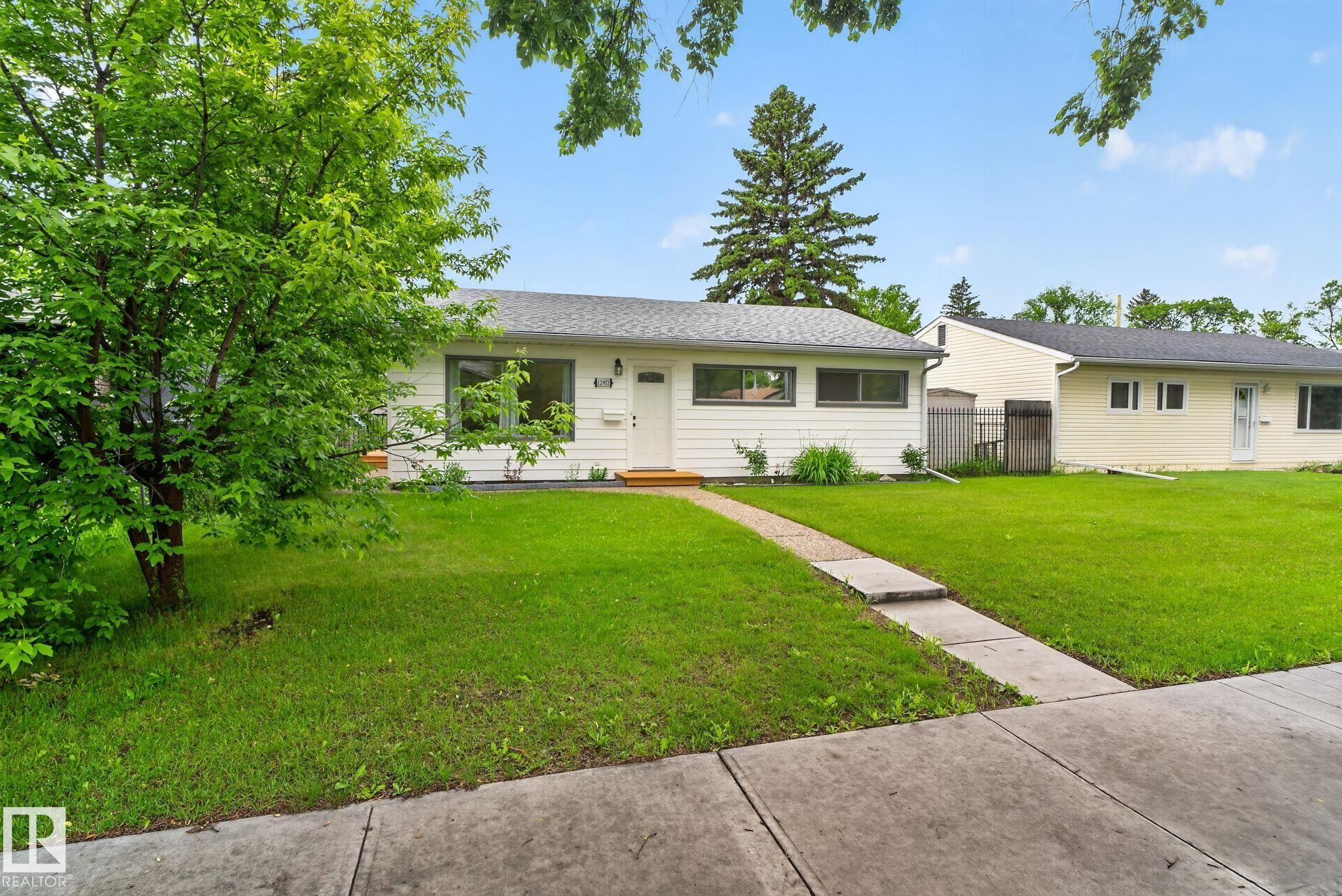 Single-story residence featuring white siding, a dark shingle roof, and multiple windows - 12952 114 Street Nw, Edmonton, AB