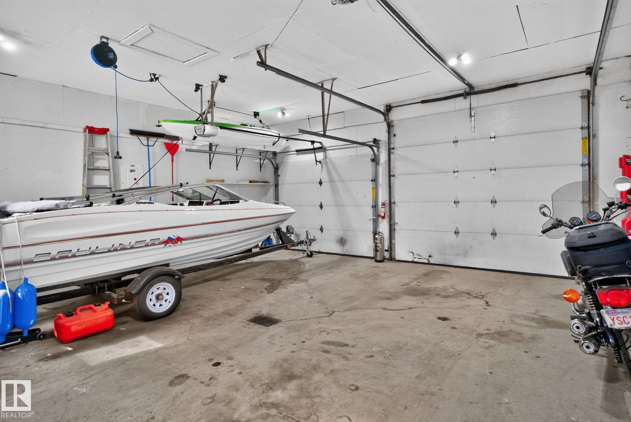 Spacious garage featuring concrete flooring and two overhead doors - 12952 114 Street Nw, Edmonton, AB
