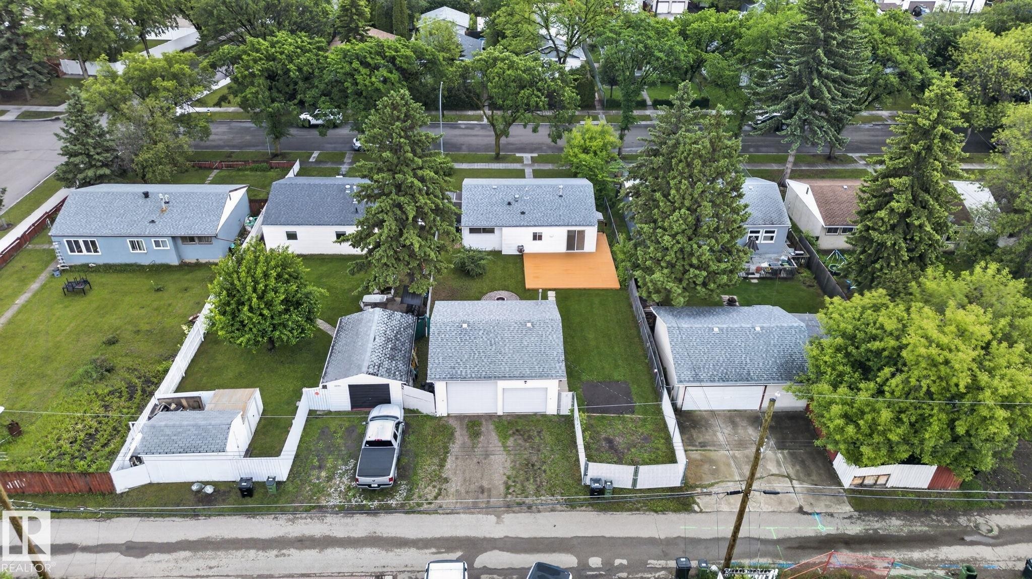 Residential property featuring a detached double garage with a paved driveway, a separate shed, and a fenced backyard - 12952 114 Street Nw, Edmonton, AB