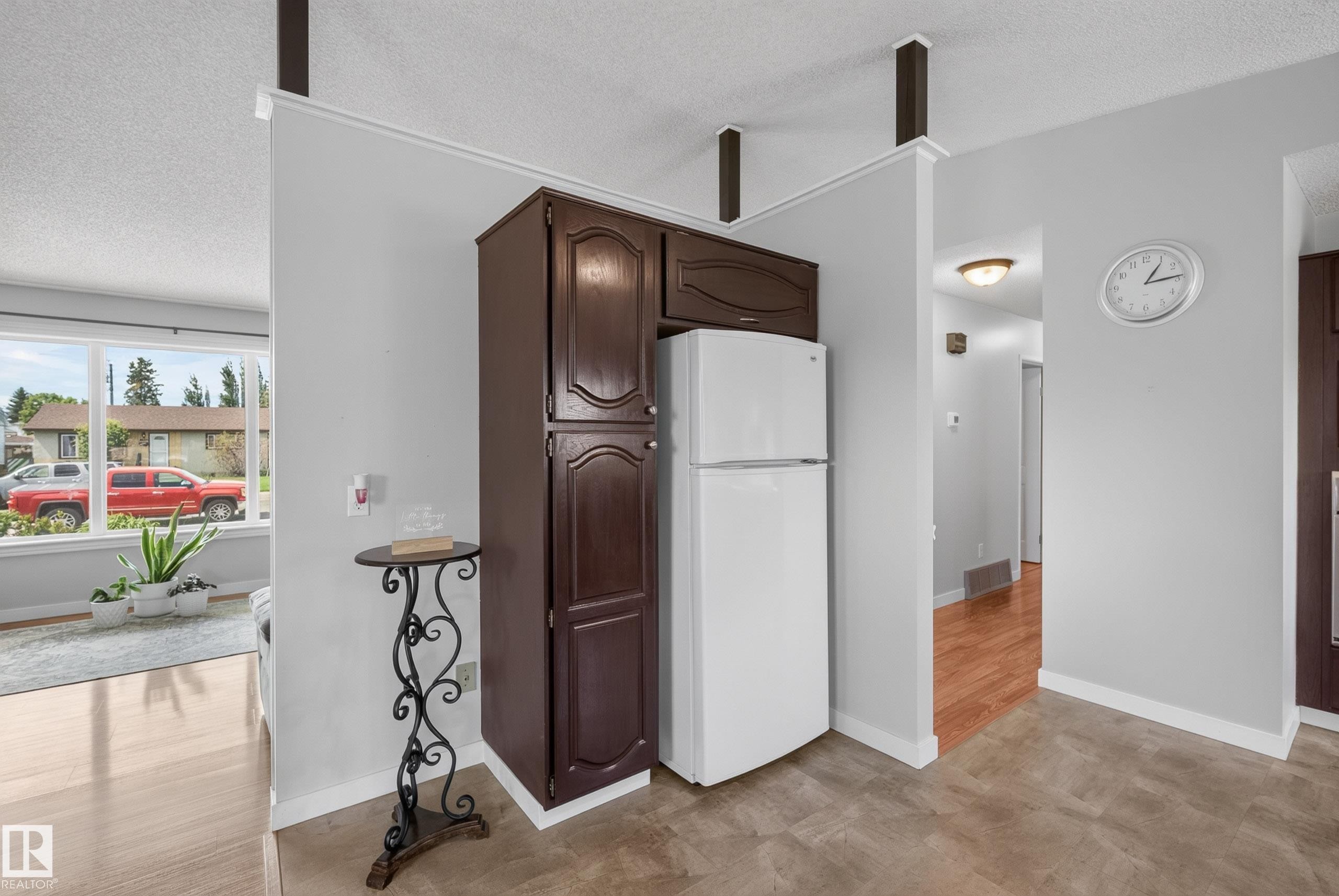 Kitchen area featuring dark wood-finish cabinetry, an included white refrigerator, and durable flooring - 10935 152 Street, Edmonton, AB