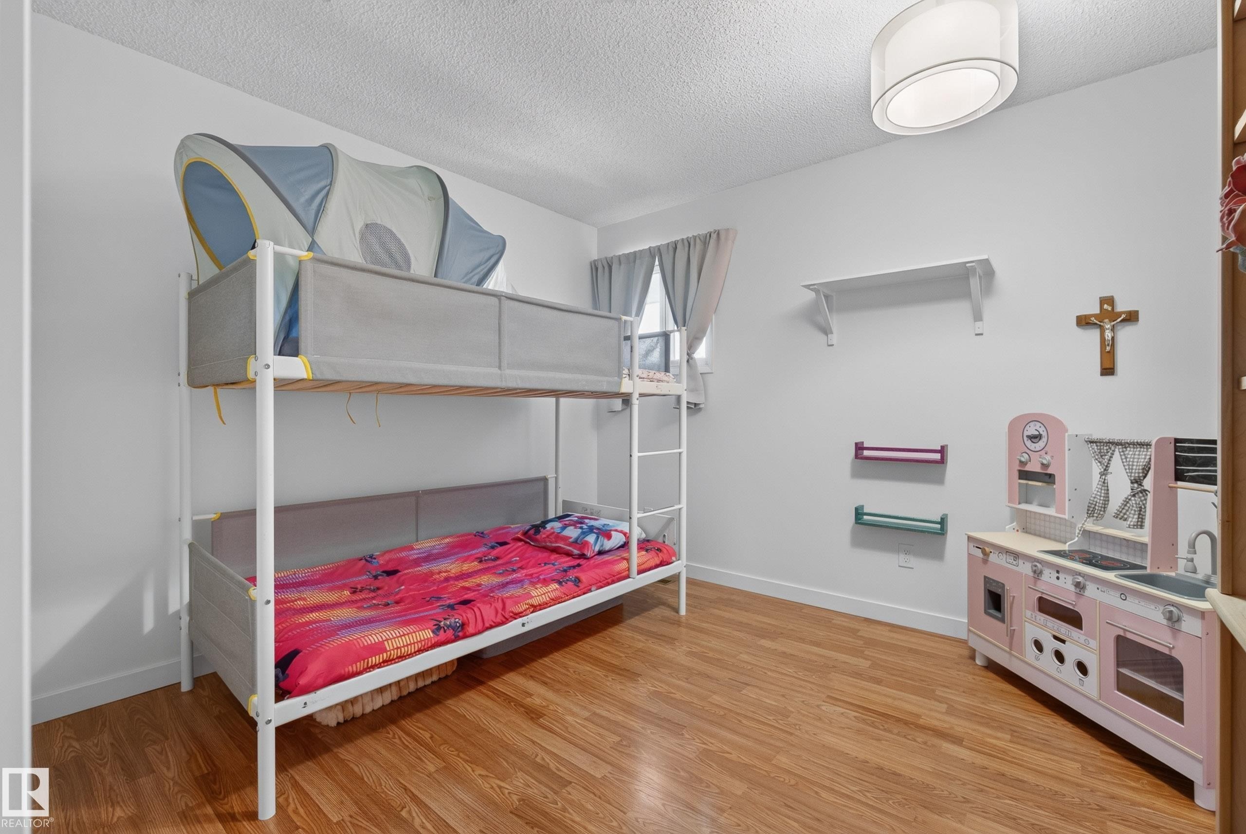 Light-filled room featuring wood-finish flooring, white walls, and a ceiling-mounted light fixture - 10935 152 Street, Edmonton, AB