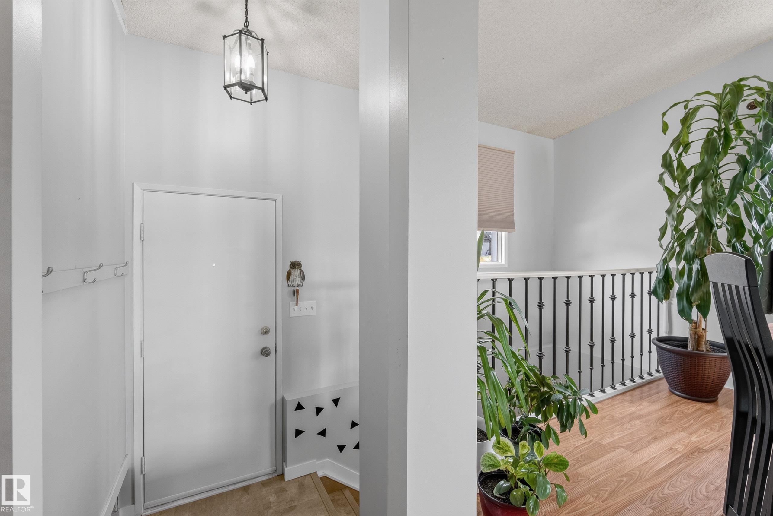 Entryway featuring a pendant light fixture, white door, and neutral wall paint - 10935 152 Street, Edmonton, AB
