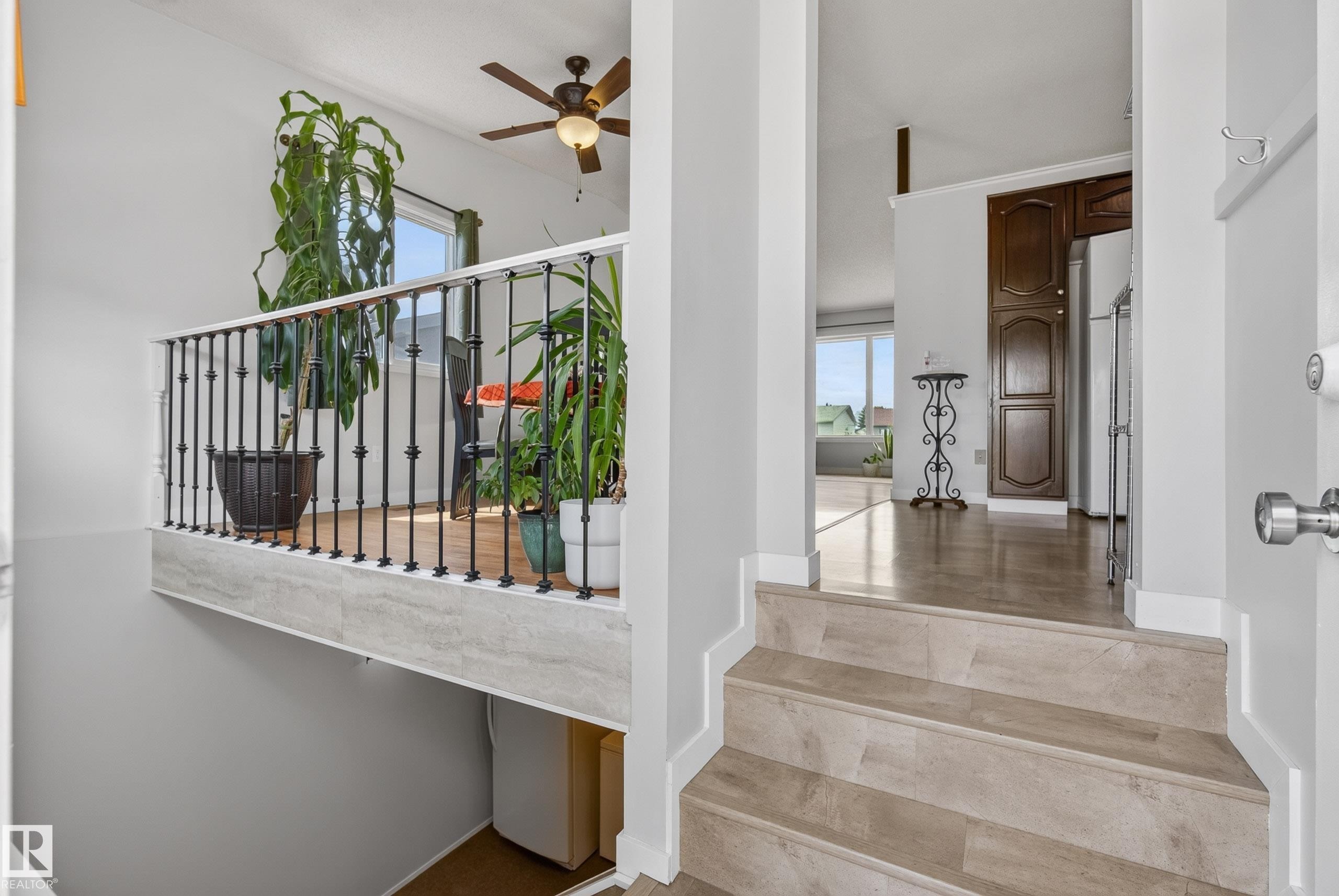 Split-level entry featuring wood-finish flooring and a decorative wrought iron railing - 10935 152 Street, Edmonton, AB
