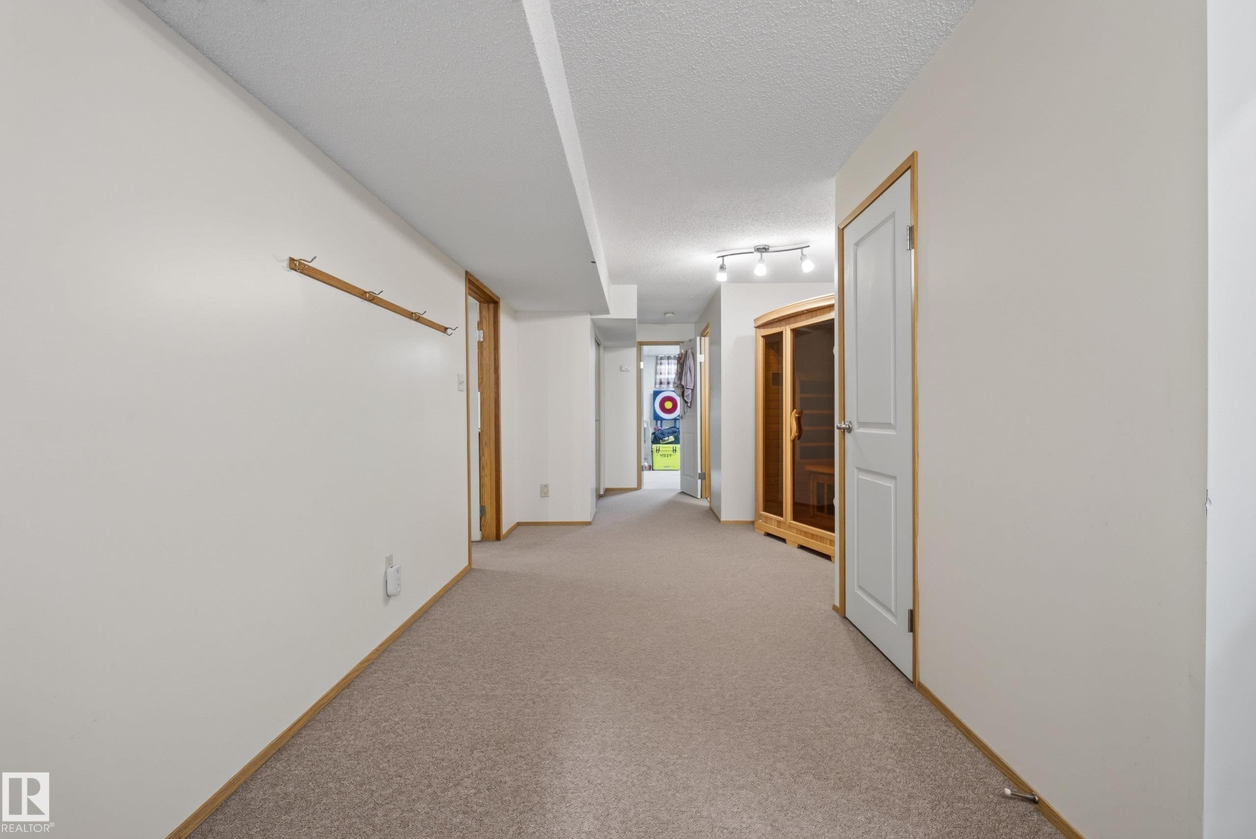 Carpeted hallway featuring white walls, light wood trim, recessed ceiling, and track lighting fixture - 10935 152 Street, Edmonton, AB