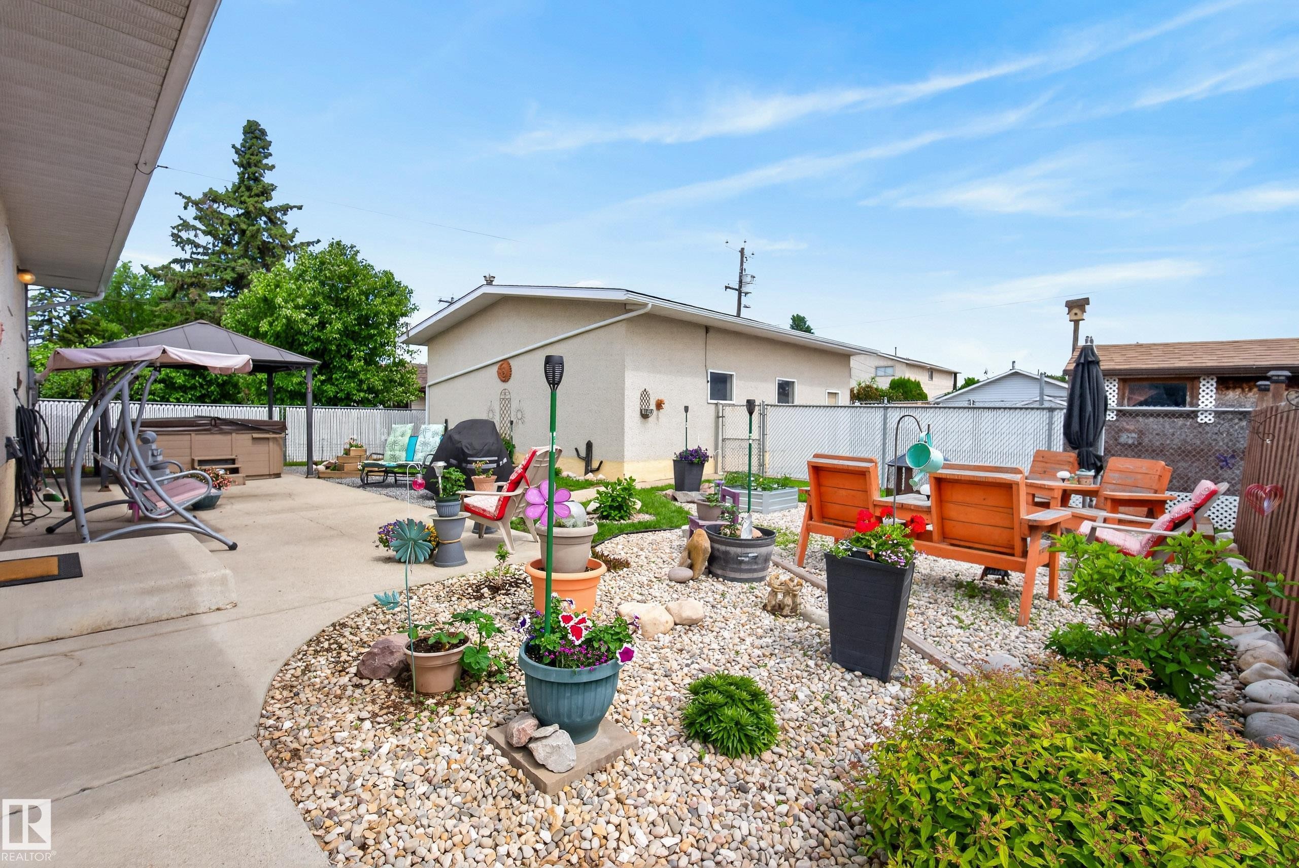 Outdoor living area featuring a concrete patio, gravel landscaping, and a built-in hot tub under a gazebo - 10935 152 Street, Edmonton, AB