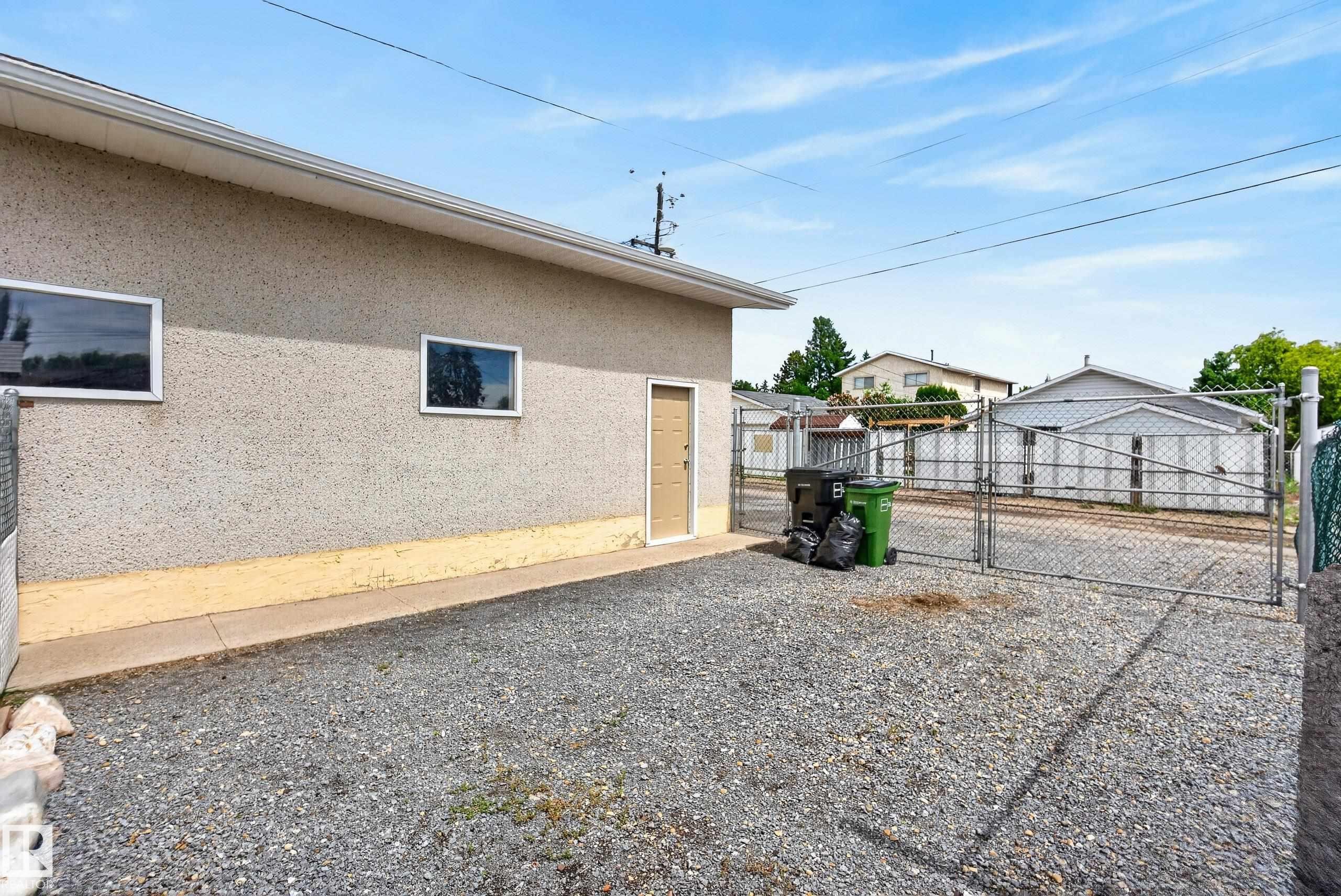 Exterior building featuring stucco siding, two horizontal windows, and a side entry door - 10935 152 Street, Edmonton, AB