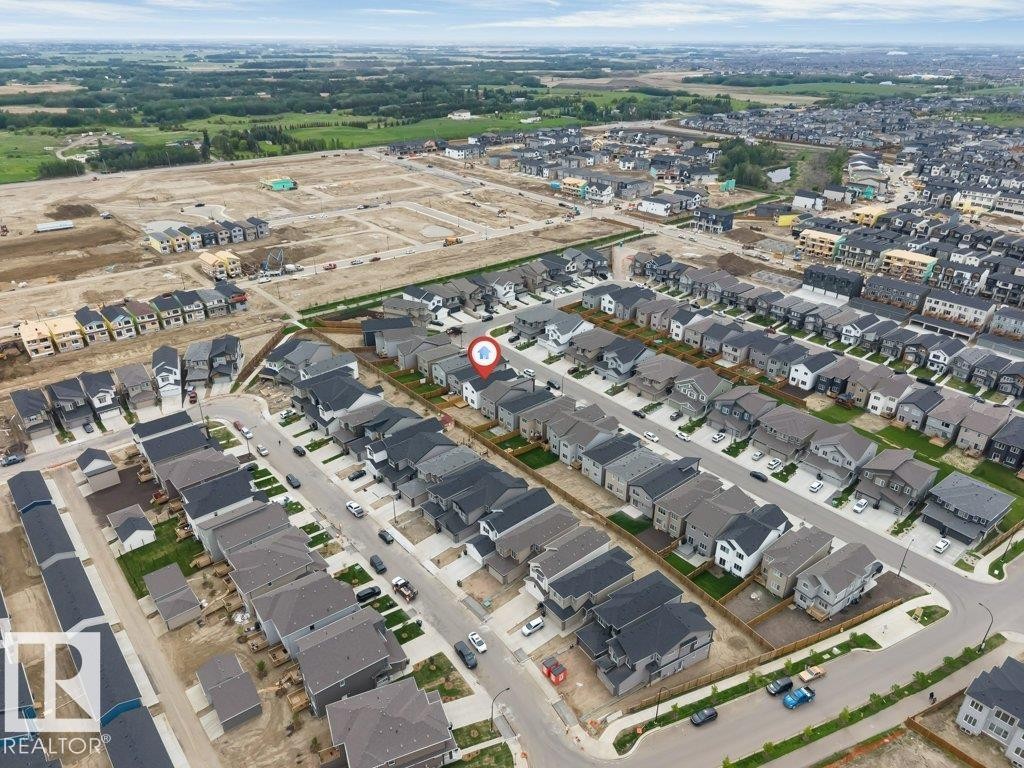 Aerial perspective of a developing residential community, featuring numerous single-family homes with dark-toned roofing and light-colored siding - 423 28 Street, Edmonton, AB