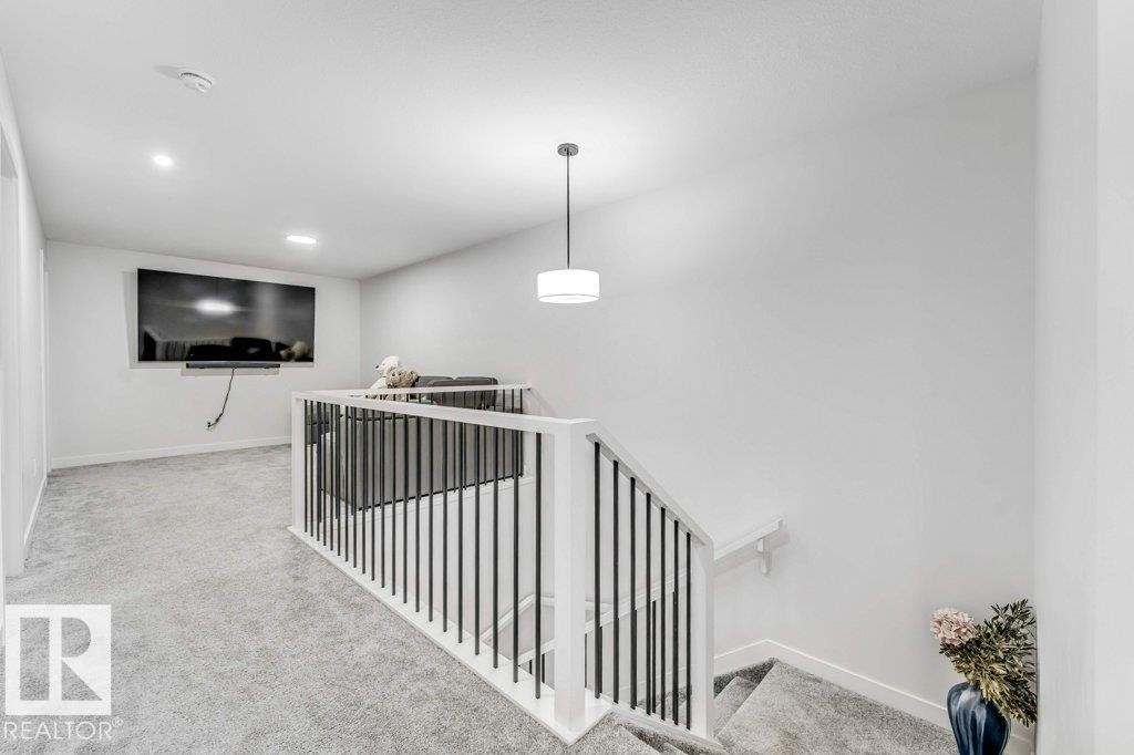 Upper level landing featuring carpeted flooring and a contemporary white handrail with black iron balusters - 423 28 Street, Edmonton, AB