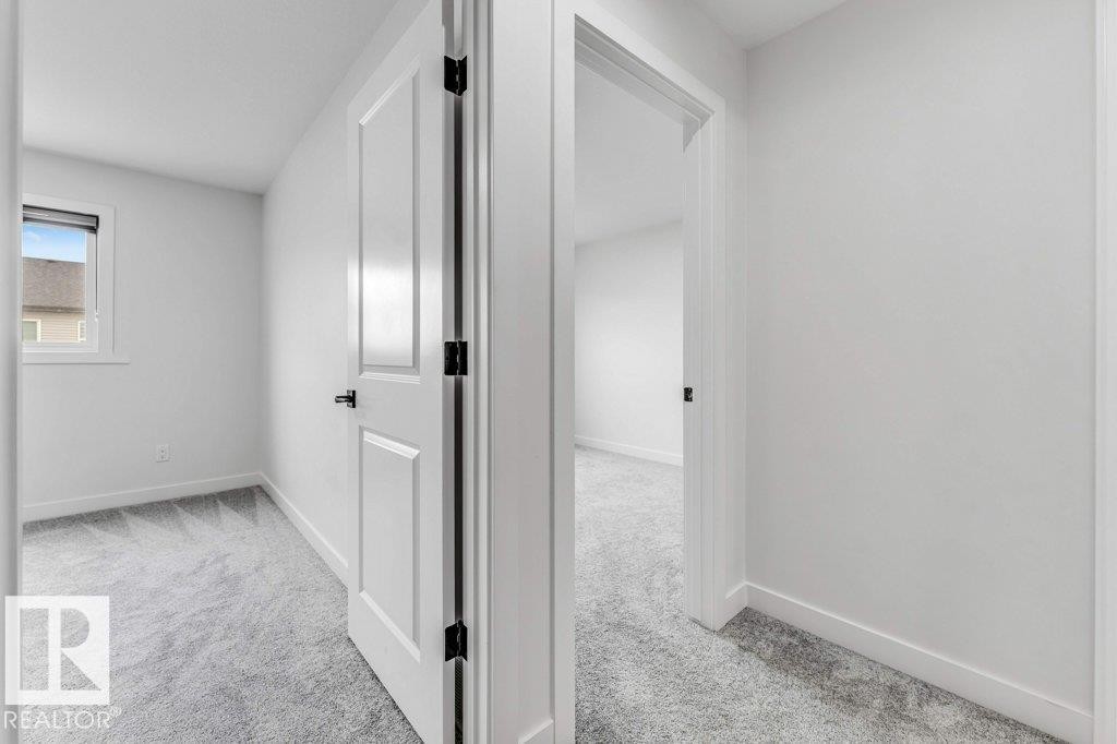 White paneled interior door with black hardware, complementing light gray carpeting - 423 28 Street, Edmonton, AB