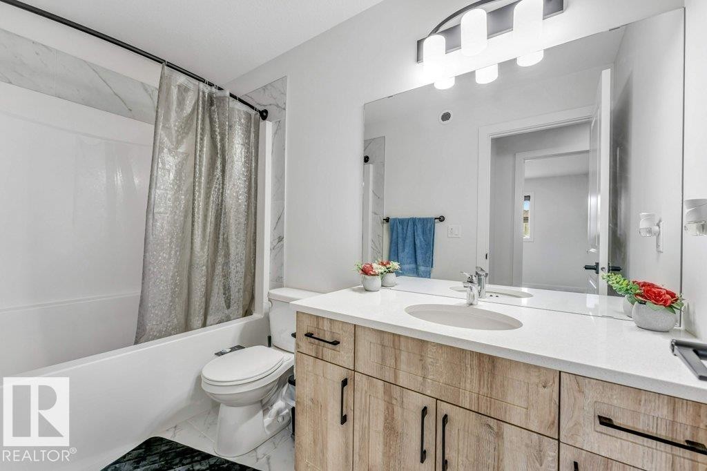 Bathroom featuring a wood-look vanity with black hardware, a white countertop, and an integrated sink - 423 28 Street, Edmonton, AB