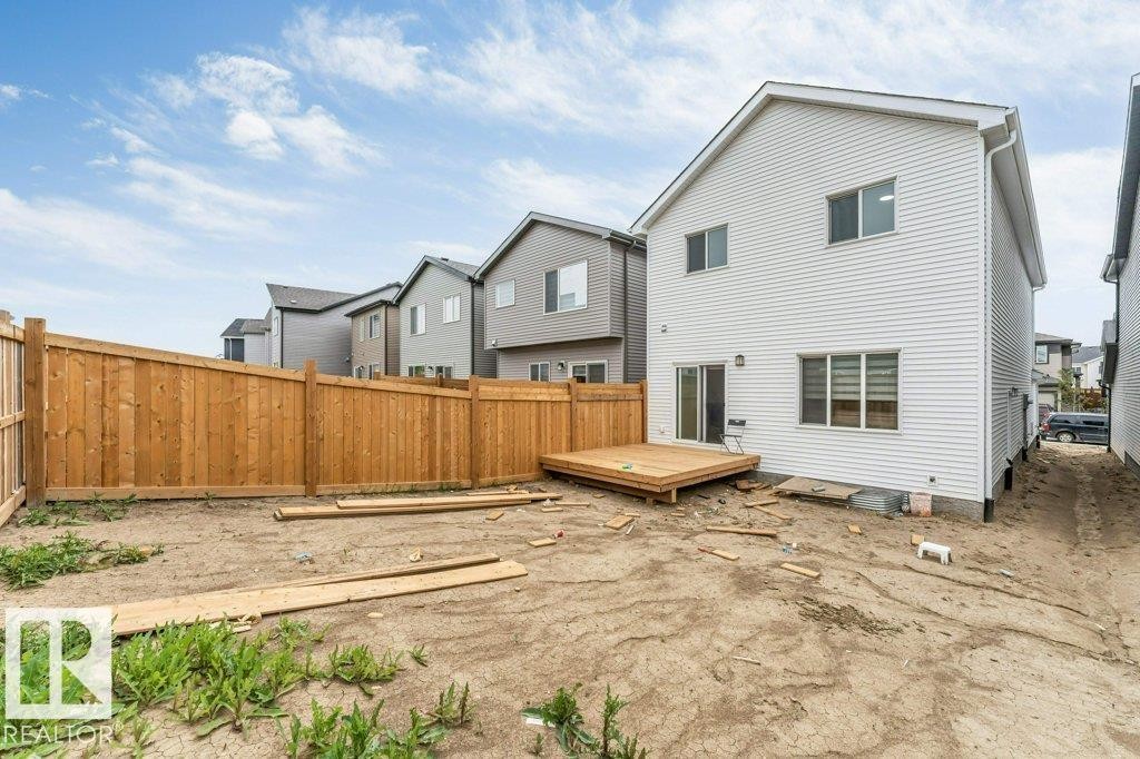 Rear exterior featuring a ground-level deck, white vinyl siding, and multiple windows - 423 28 Street, Edmonton, AB