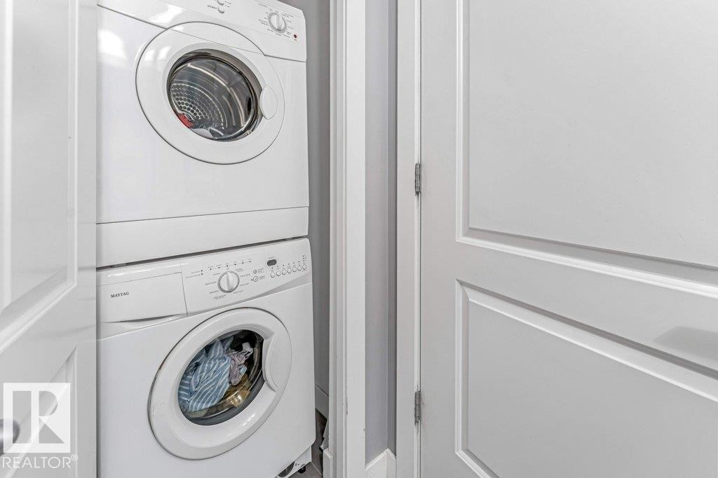 Compact laundry area featuring a stacked washer and dryer unit - 401 667 Watt Boulevard, Edmonton, AB