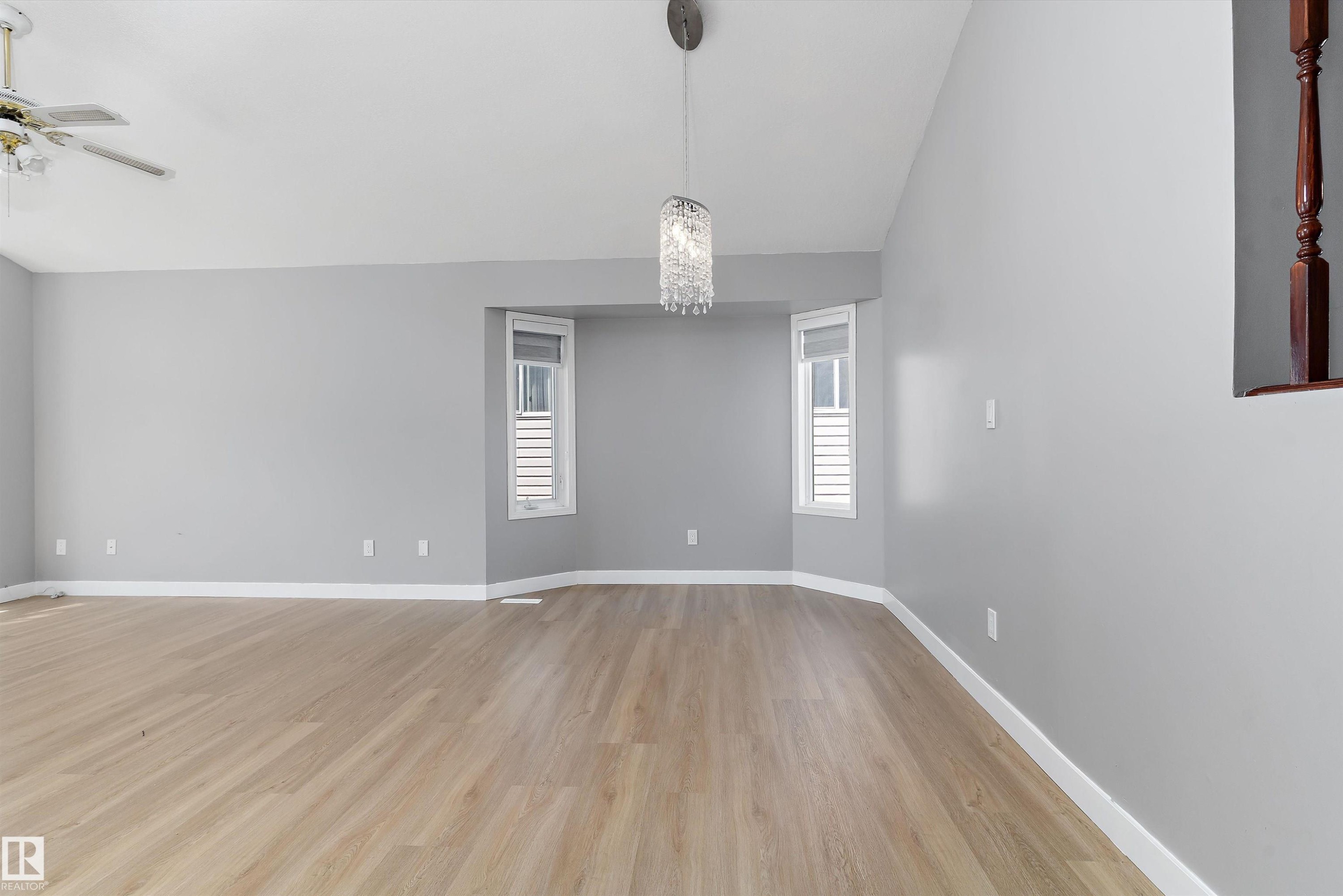 Spacious room featuring light wood-finish flooring, light gray wall paint, and white baseboards - 14707 33 Street, Edmonton, AB