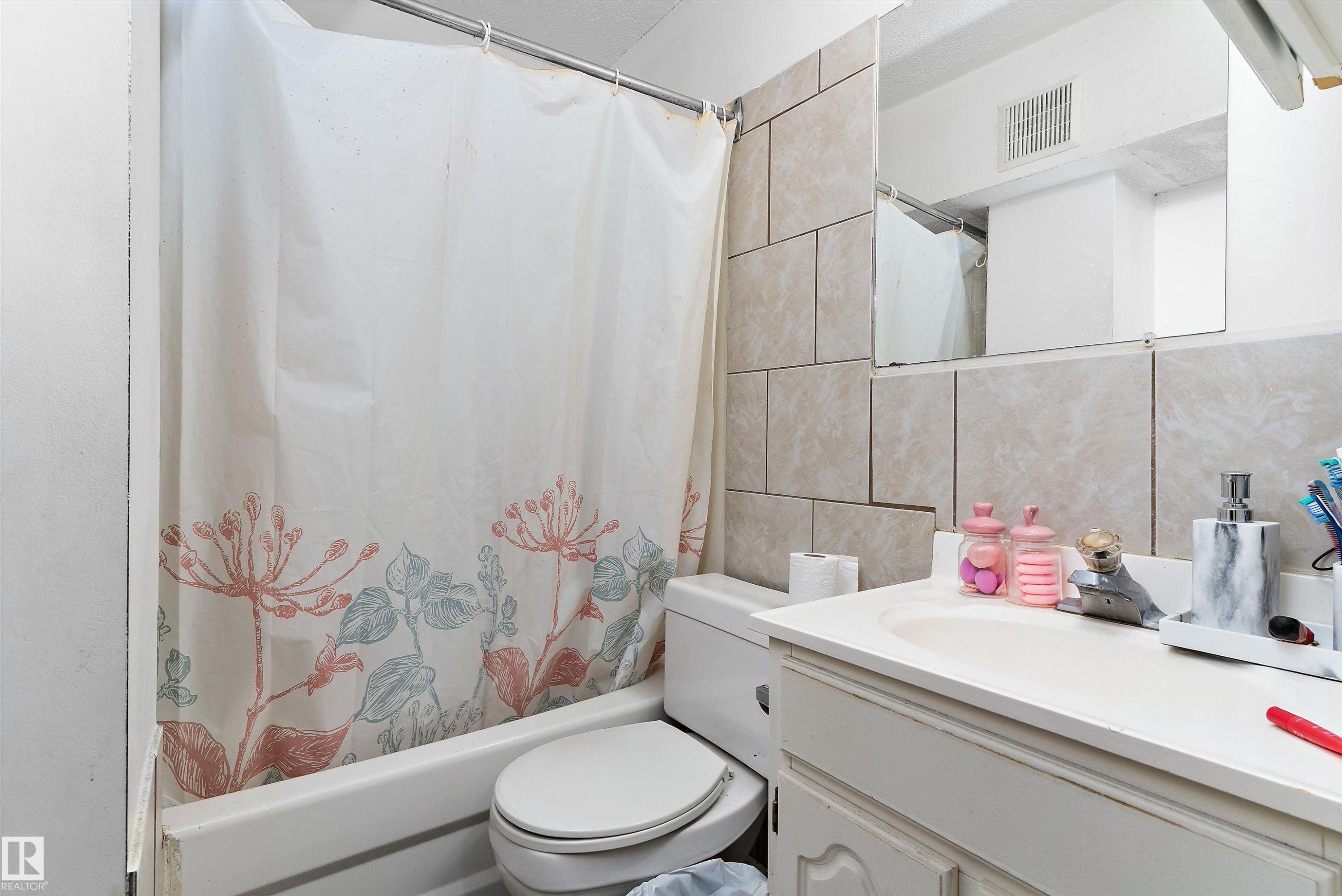 Bathroom featuring a white bathtub, toilet, and a vanity with an integrated sink - 14707 33 Street, Edmonton, AB