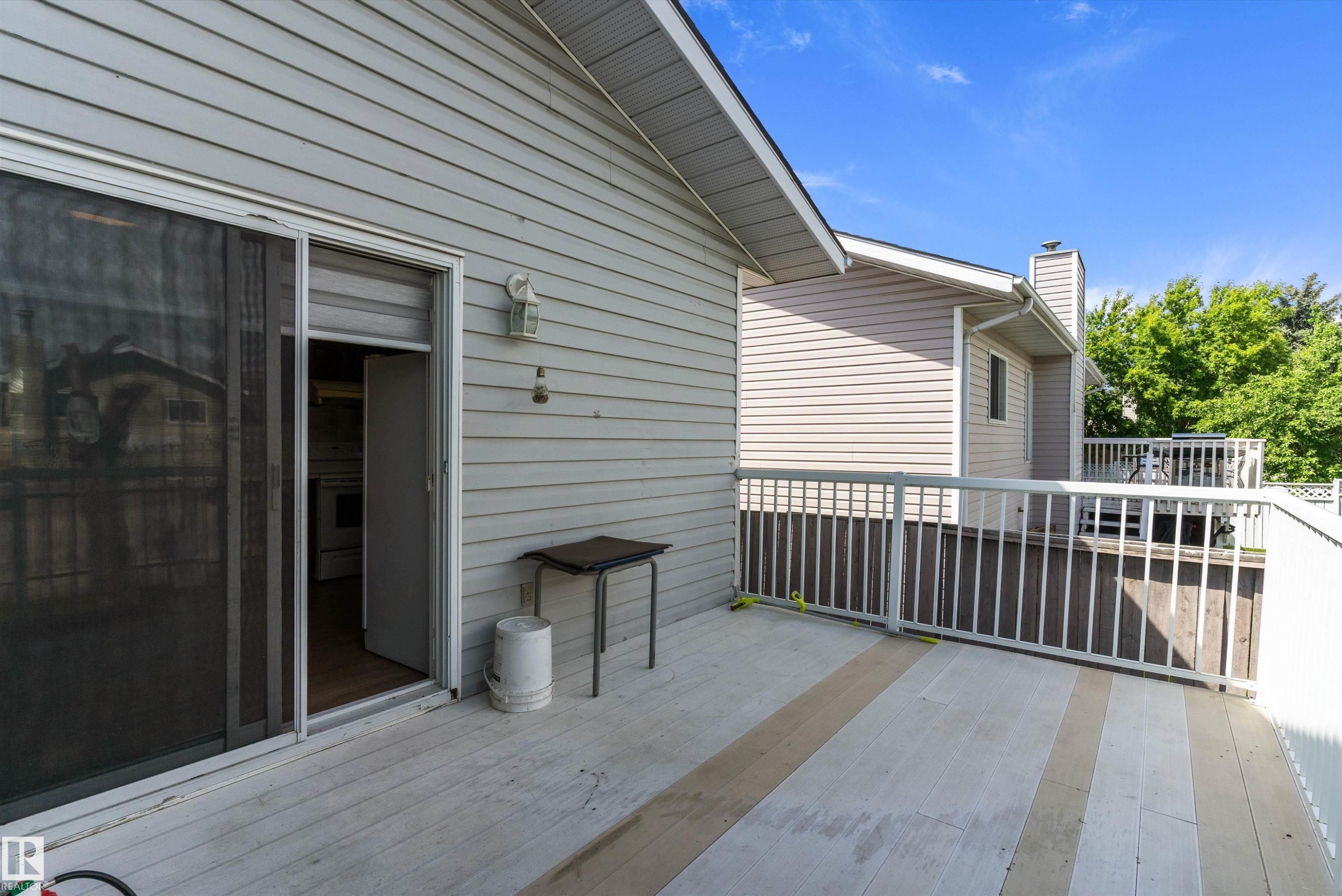 Outdoor deck featuring wide plank flooring with alternating tones, white railing, and exterior wall siding - 14707 33 Street, Edmonton, AB