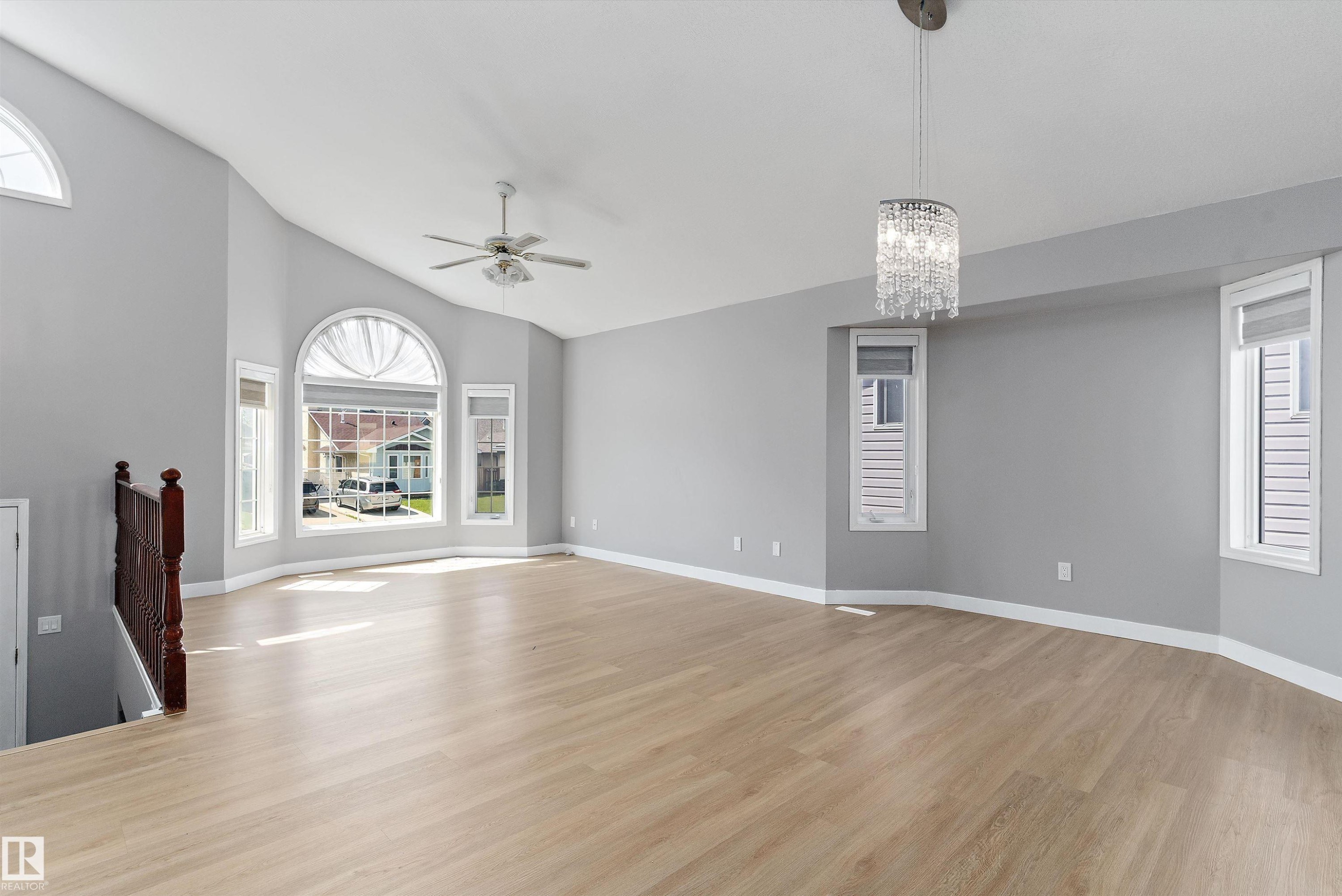 Spacious room featuring vaulted ceilings, light wood-finish flooring, and multiple windows including a prominent arched window - 14707 33 Street, Edmonton, AB