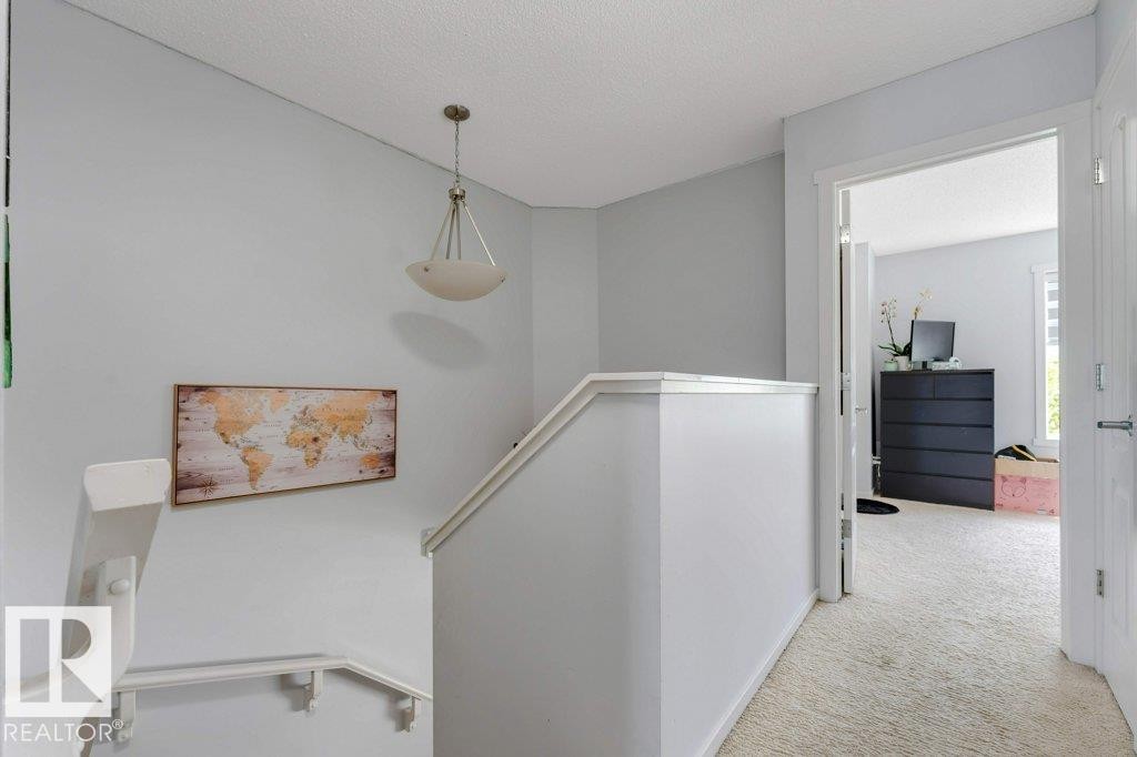 Upper landing featuring light gray walls, white trim, a semi-flush mount ceiling light, and plush light-colored carpeting - 3511 15A Street, Edmonton, AB
