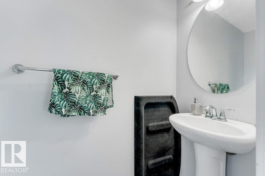 Pedestal sink with chrome faucet, complemented by a round wall-mounted mirror - 3511 15A Street, Edmonton, AB