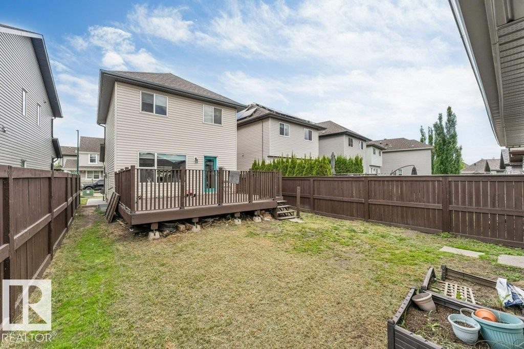Expansive backyard featuring a large wood deck with railings, a turquoise exterior door, and full perimeter wood fencing - 3511 15A Street, Edmonton, AB