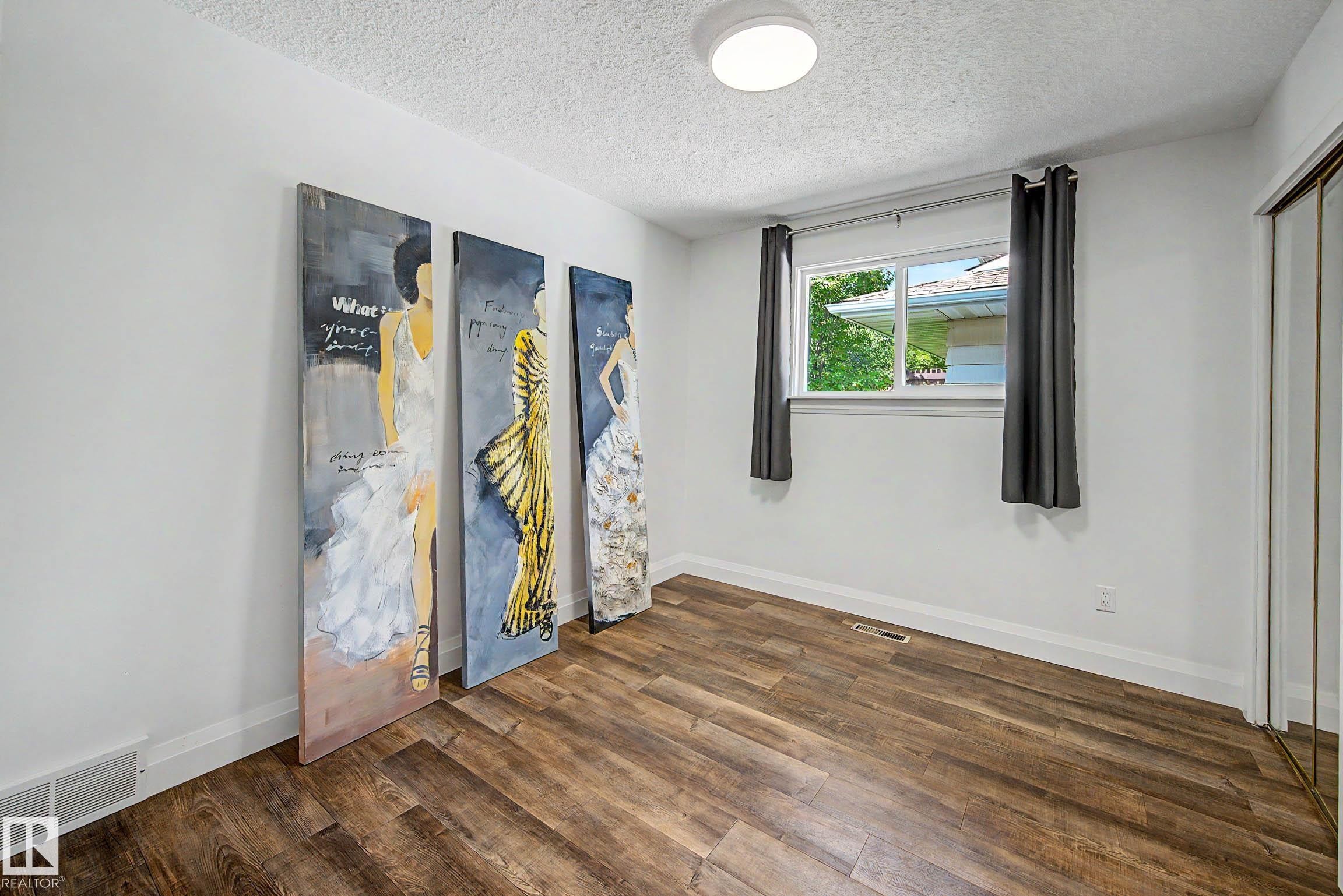 Room featuring wood-finish flooring, white walls, and a window with a white frame - 3718 103B Street Nw, Edmonton, AB - Indoor Photo Showing Other Room