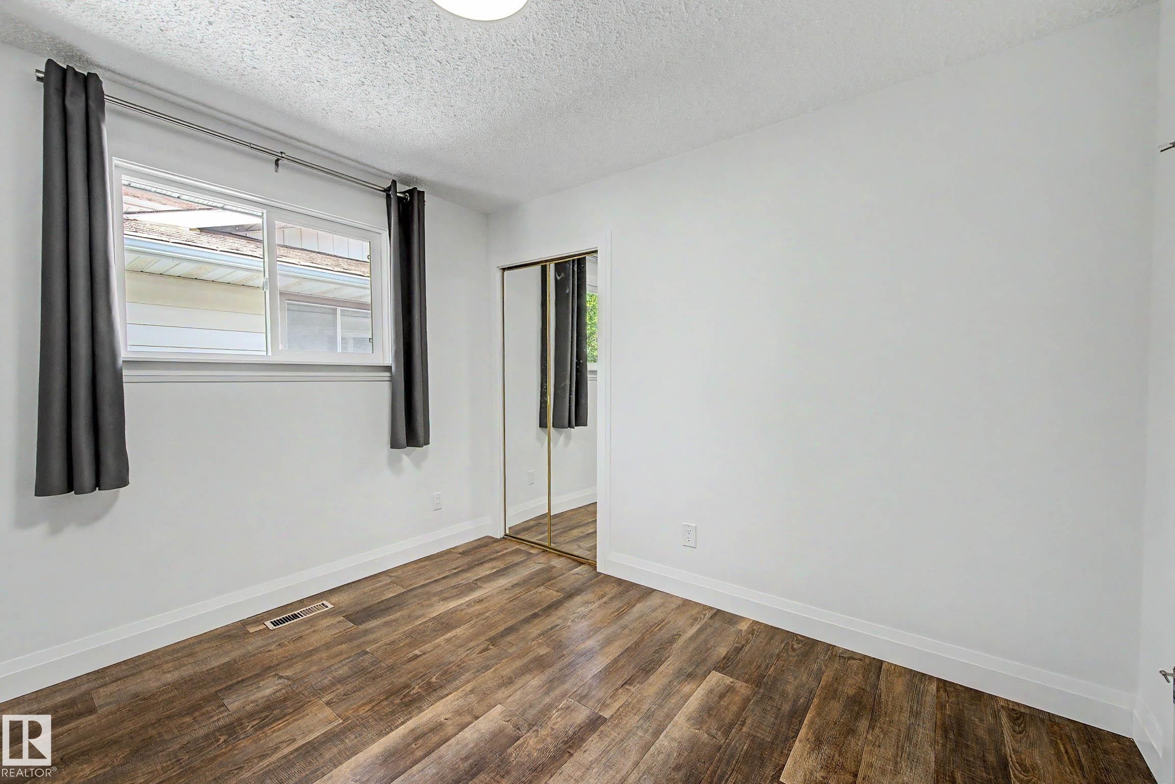 Bright room featuring wood-finish flooring, white walls, and a large window - 3718 103B Street Nw, Edmonton, AB - Indoor Photo Showing Other Room