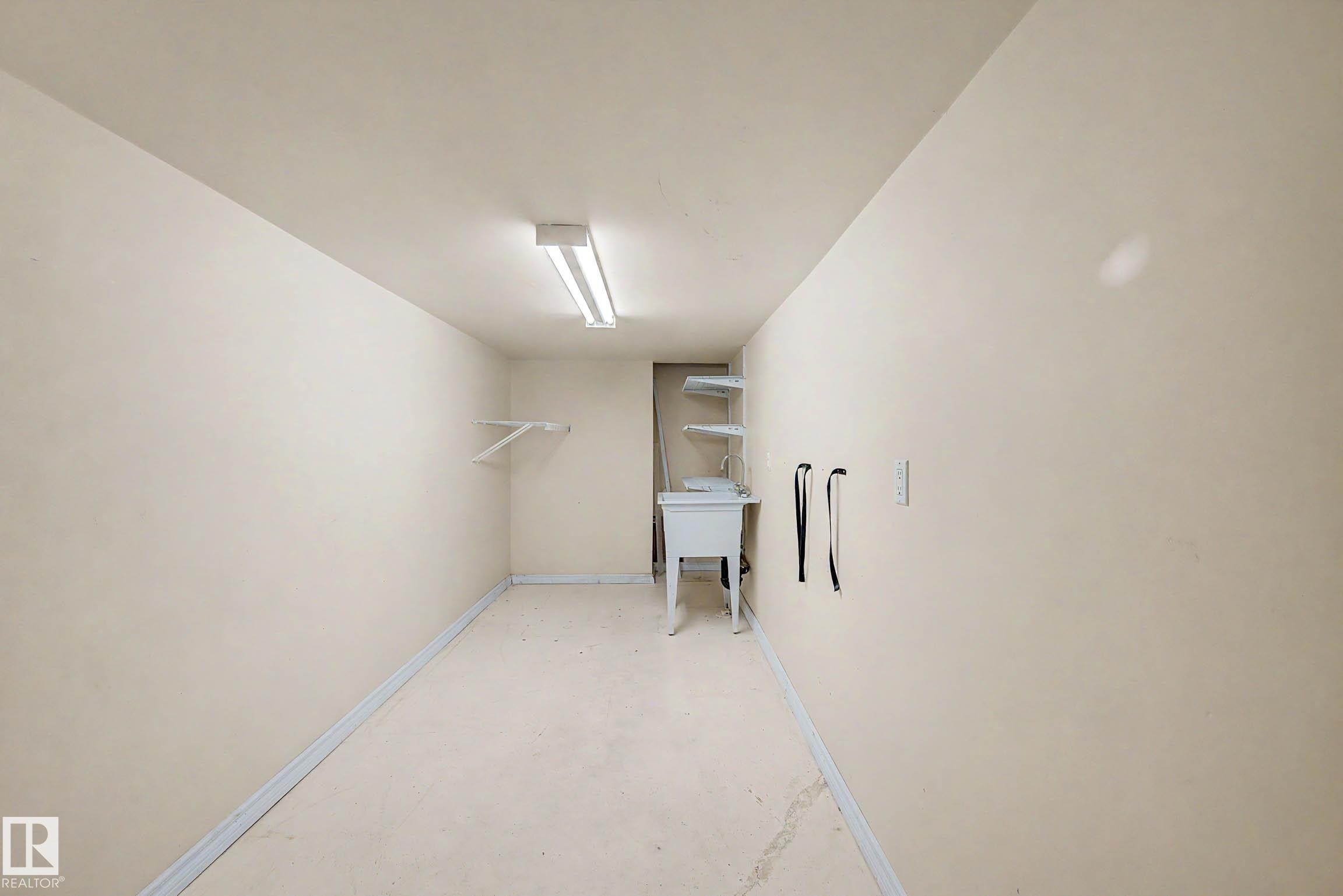Dedicated utility space featuring a utility sink, wall-mounted shelving, and overhead fluorescent lighting - 3718 103B Street Nw, Edmonton, AB - Indoor Photo Showing Other Room