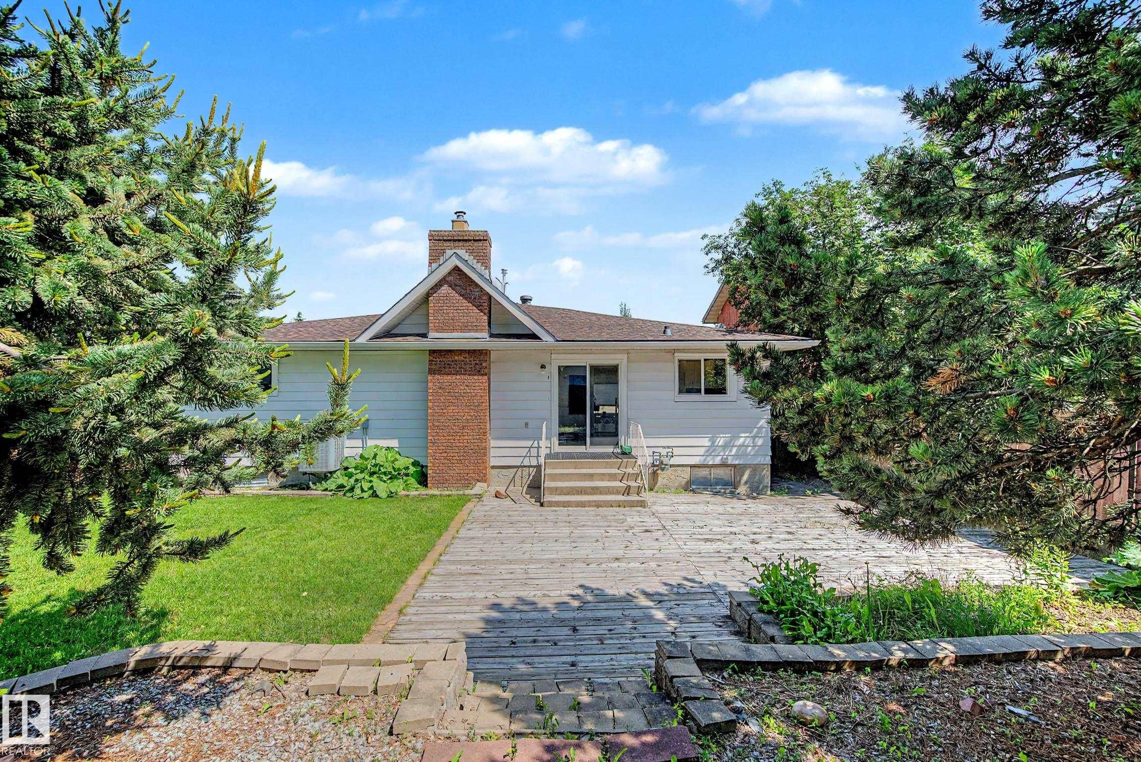 Rear exterior featuring a brick chimney, white siding, and a sliding glass door - 3718 103B Street Nw, Edmonton, AB - Outdoor