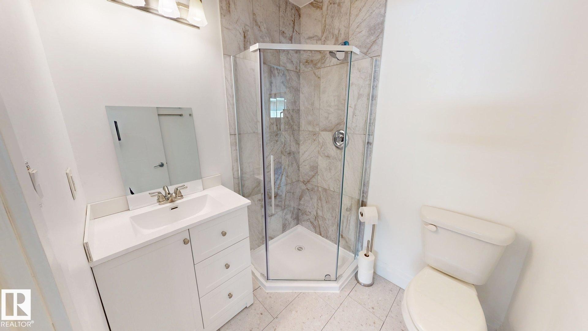 Corner glass-enclosed shower with stone-patterned tile surround - 3718 103B Street, Edmonton, AB