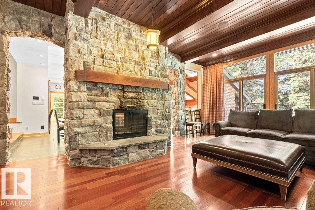 Family room featuring two sided wood burning fireplace, Brazilian Cherry hardwood flooring with custom millwork and wood ceiling. - 738 Wheeler Road, Edmonton, AB
