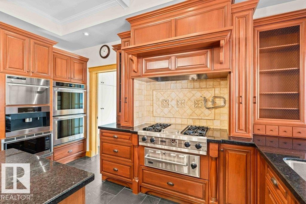 Kitchen with granite countertops, custom tile backsplash, Miele, Subzero and KitchenAid appliances featuring trash compactor, dual wall ovens plus garburator. - 738 Wheeler Road, Edmonton, AB