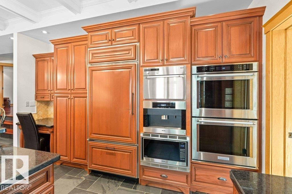 Kitchen with granite countertops, custom tile backsplash, Miele, Subzero and KitchenAid appliances featuring trash compactor, dual wall ovens plus garburator. - 738 Wheeler Road, Edmonton, AB