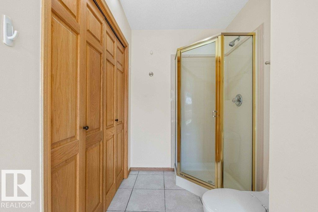 Full bathroom featuring light tile patterned flooring, a stall shower, and a closet - 738 Wheeler Road, Edmonton, AB