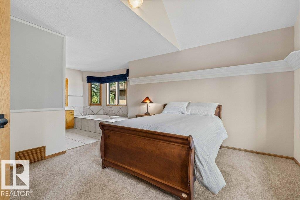 Bedroom with light carpet, connected bathroom, and light tile patterned floors - 738 Wheeler Road, Edmonton, AB