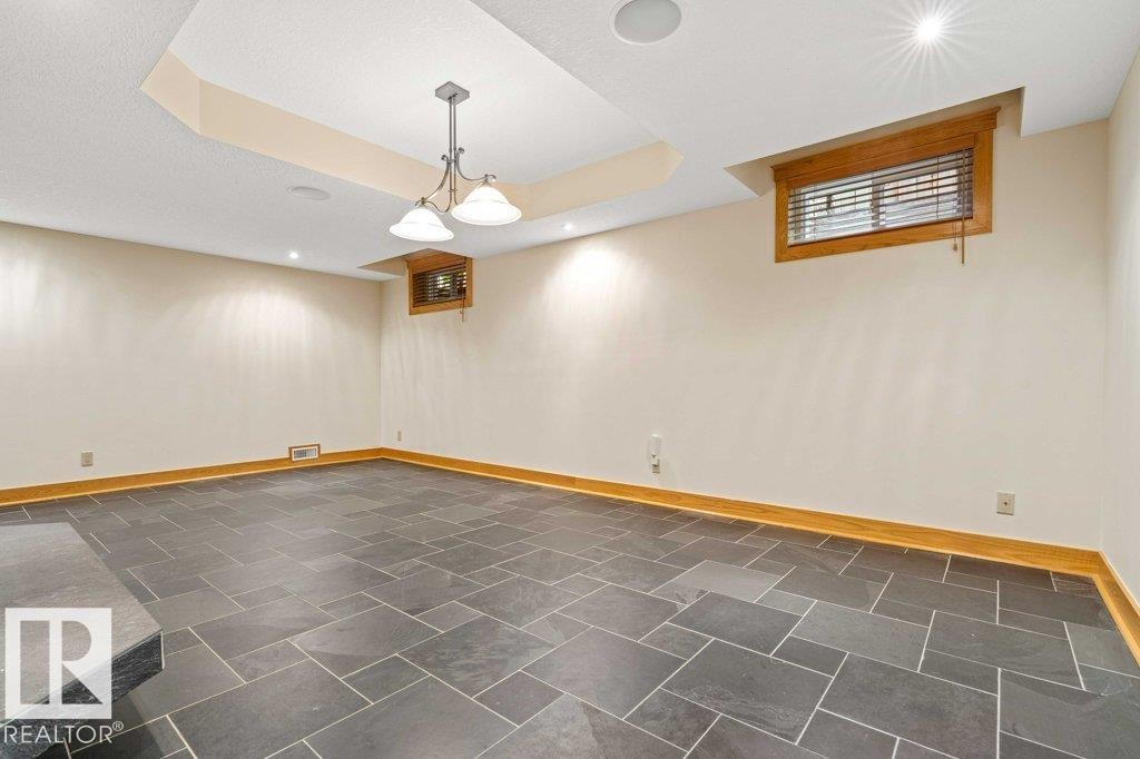 Rec room with two sided wood burning fireplace, heated slate flooring and flush mounted ceiling speakers. - 738 Wheeler Road, Edmonton, AB