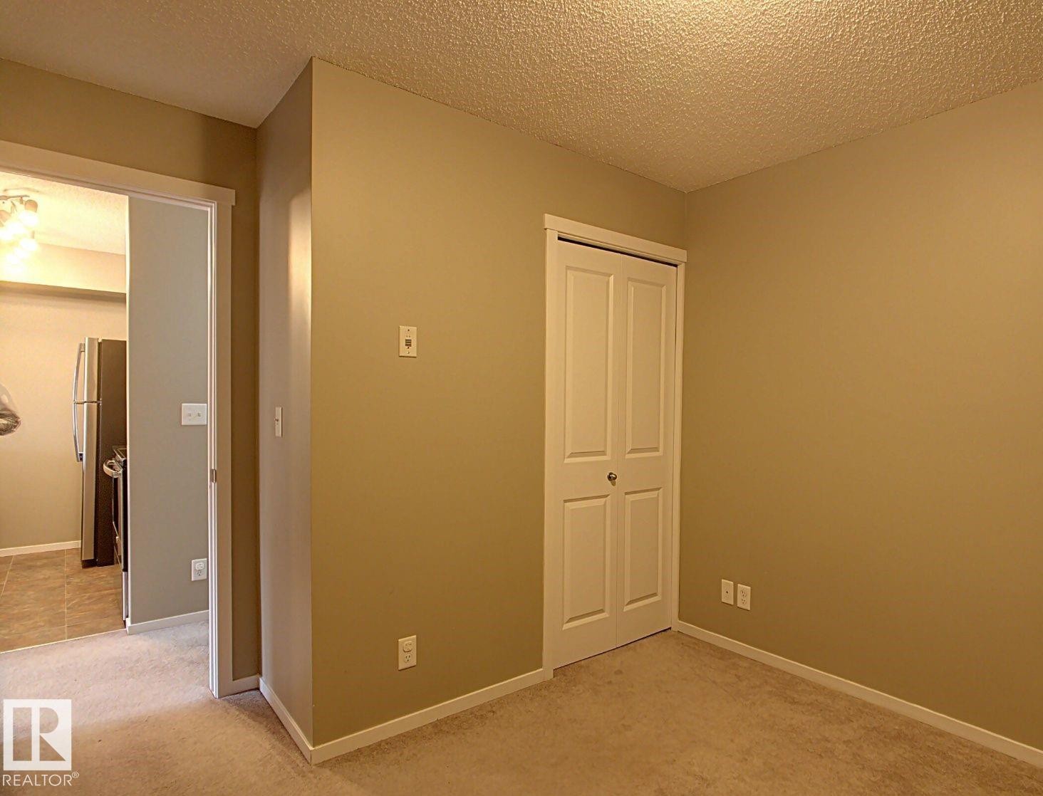 Neutral-toned room with plush carpet flooring, a bifold closet, and white trim - 328 3315 James Mowatt Trail, Edmonton, AB